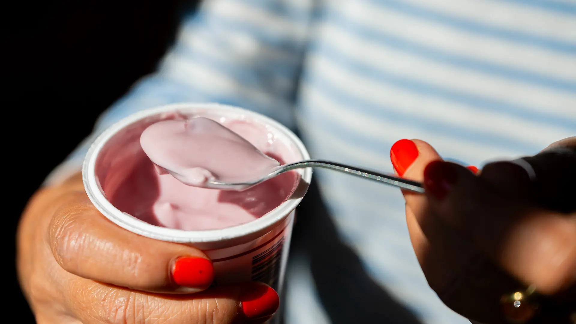 Eine Frau hält am 28.07.2026 in Berlin einen Becher Kirschjoghurt in den Haenden.