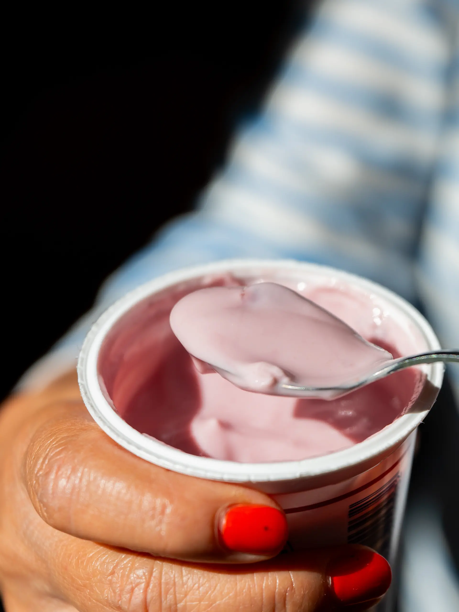 Eine Frau hält am 28.07.2026 in Berlin einen Becher Kirschjoghurt in den Haenden. 