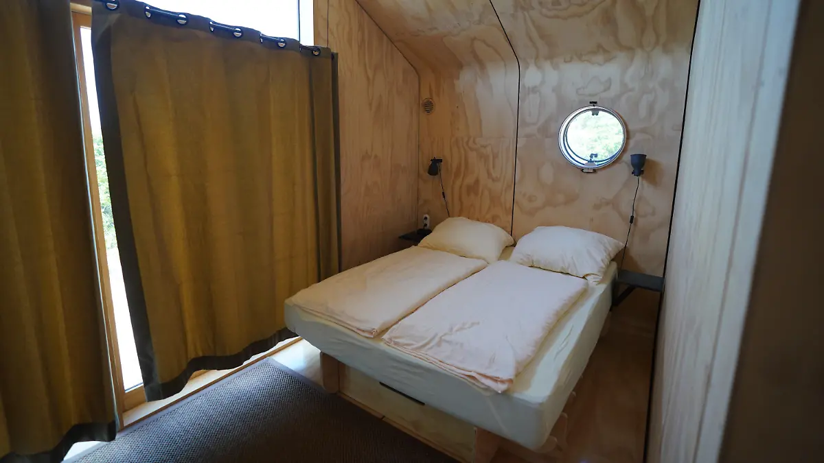16.06.2021, Schleswig-Holstein, Helgoland: Blick in das Schlafzimmer in einem sogenannten Wikkelhouse auf der Helgoländer Düne. Die beiden sogenannten Wikkelhouses aus einer Manufaktur in Amsterdam sind nach Angaben des Helgoland Tourismus-Services für diese Saison ausgebucht. Auch im kommenden Jahr sind die Tiny Houses, die nur online und wochenweise gebucht werden können, bereits belegt. Die kleinen Häuser, deren Wände im Kern aus 24 miteinander verwickelter Schichten Pappe bestehen, sind komplett ausgestattet - es gibt aber kein Wasser und keine Toilette. (zu dpa «Gefragte Pappe: Helgoland möchte mehr Wikkelhouses») Foto: Marcus Brandt/dpa +++ dpa-Bildfunk +++