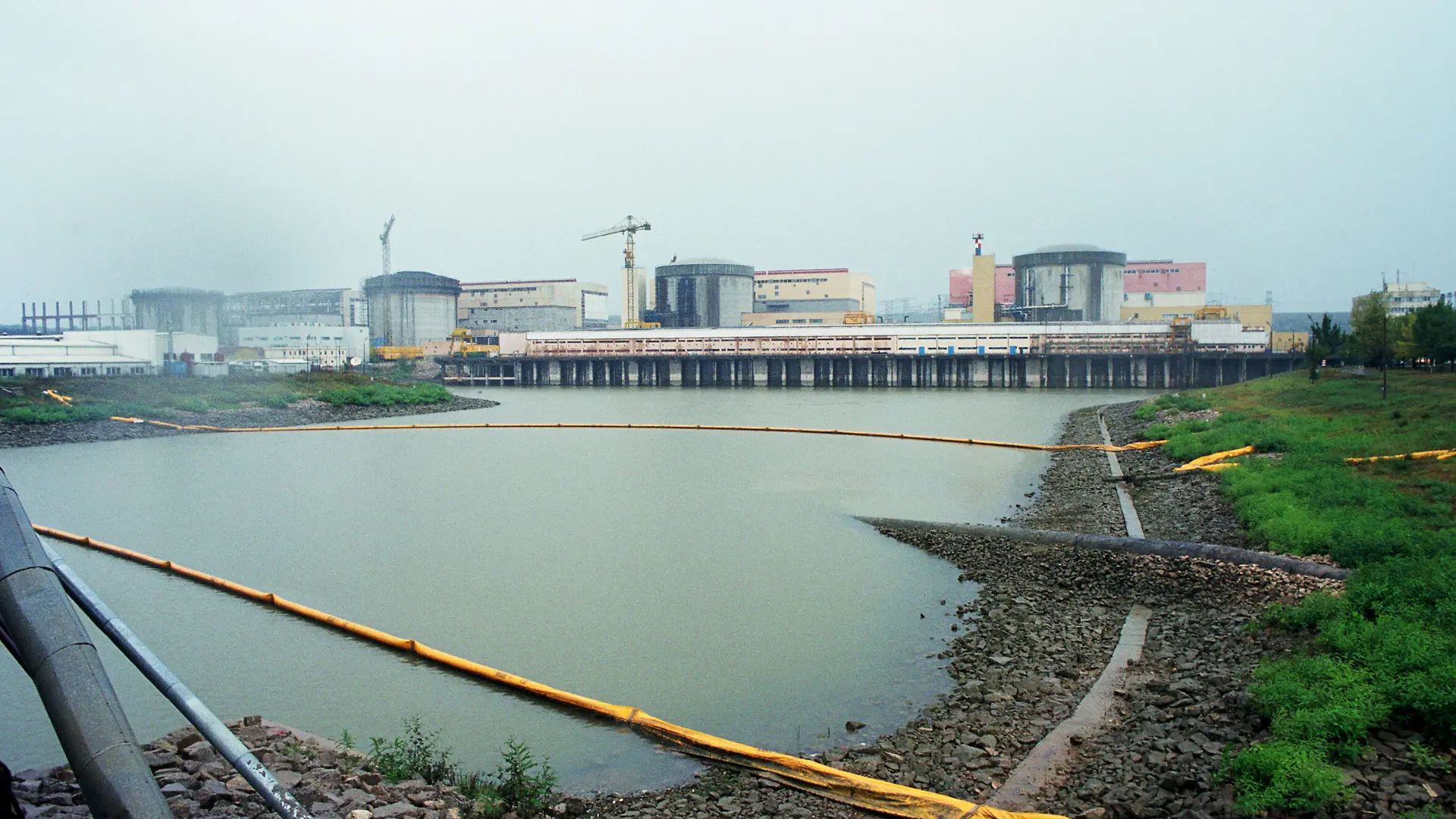 22.09.2005, Cernavoda, Constanta, Rumaenien - Blick ueber das Kuehlwasserbassin zum Atomkraftwerk Cernavoda. Das Kraftwerk arbeitet mit CANDU-Reaktoren und deckt etwa 15% des rumaenischen Energiegebrauchs. (Rumaenien, rumaenisch, Cernavoda, Constanta, Dobrudscha, Gelaende, Wasser, Kuehlwasser, Bassin, Kuehlwasserbassin, Gebaeude, Reaktoren, Kernreaktoren, Architektur, Kraftwerk, Atomkraftwerk, AKW, Kernkraftwerk, KKW, Strom, nuklear, elektrische Energie, Atomenergie, Kernenergie, Bedarf, Energiebedarf, Strombedarf, Stromerzeugung, Kernstromerzeugung, Energieversorgung, Energetik, Kernenergetik, radioaktive, Strahlung, Radioaktivitaet, Gefahr, Wirtschaft, Symbol, Aussenaufnahme, Aussenansicht, Uebersicht, Ueberblick, QF, Rumänien, rumänisch, Gelände, Kühlwasser, Kühlwasserbassin, Gebäude, Radioaktivität, Übersicht, Überblick) 00A207832CARO.JPG