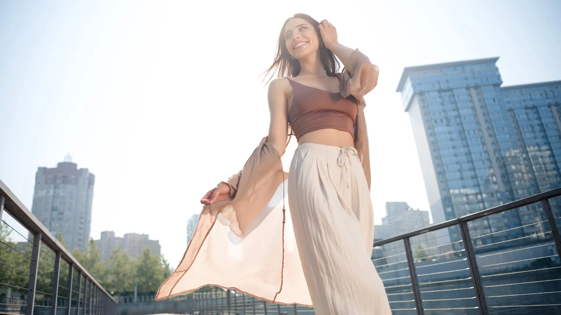 Eine Frau trägt ein sommerliches Outfit mit Palazzo-Hose und läuft durch die Stadt.