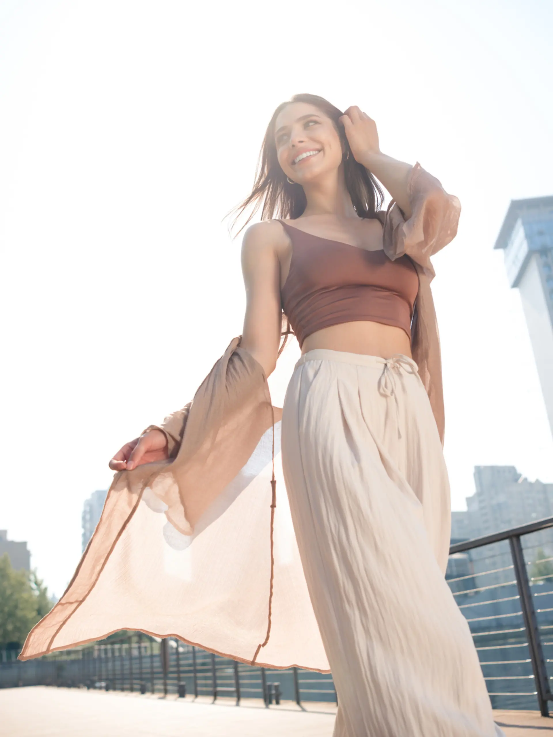 Eine Frau trägt ein sommerliches Outfit mit Palazzo-Hose und läuft durch die Stadt. 