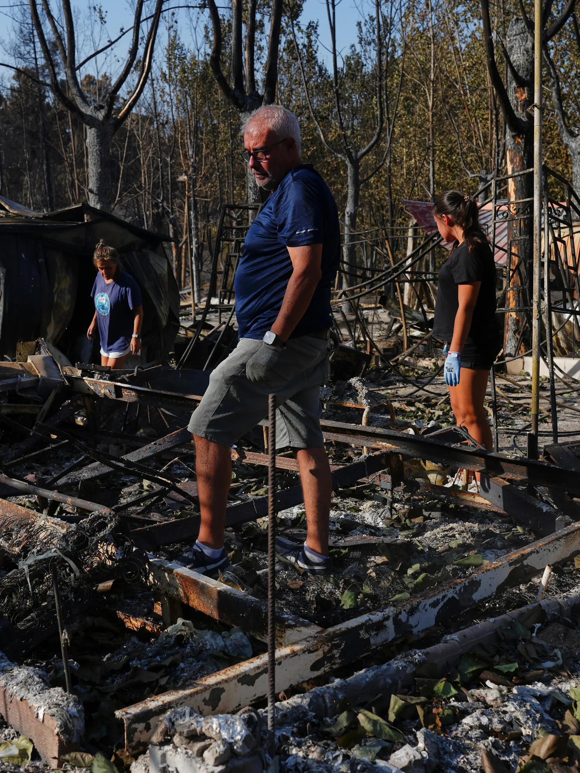 Maria del Carmen (l), ihre Tochter Maria del Carmen Lopez (r) und ihr Lebensgefährte Mario Gonzalez (M) sammeln ihre Habseligkeiten ein, nachdem ihre Bungalows auf einem Campingplatz im Valle de Iruelas in Spanien von einem Waldbrand verwüstet wurden. +++ dpa-Bildfunk +++