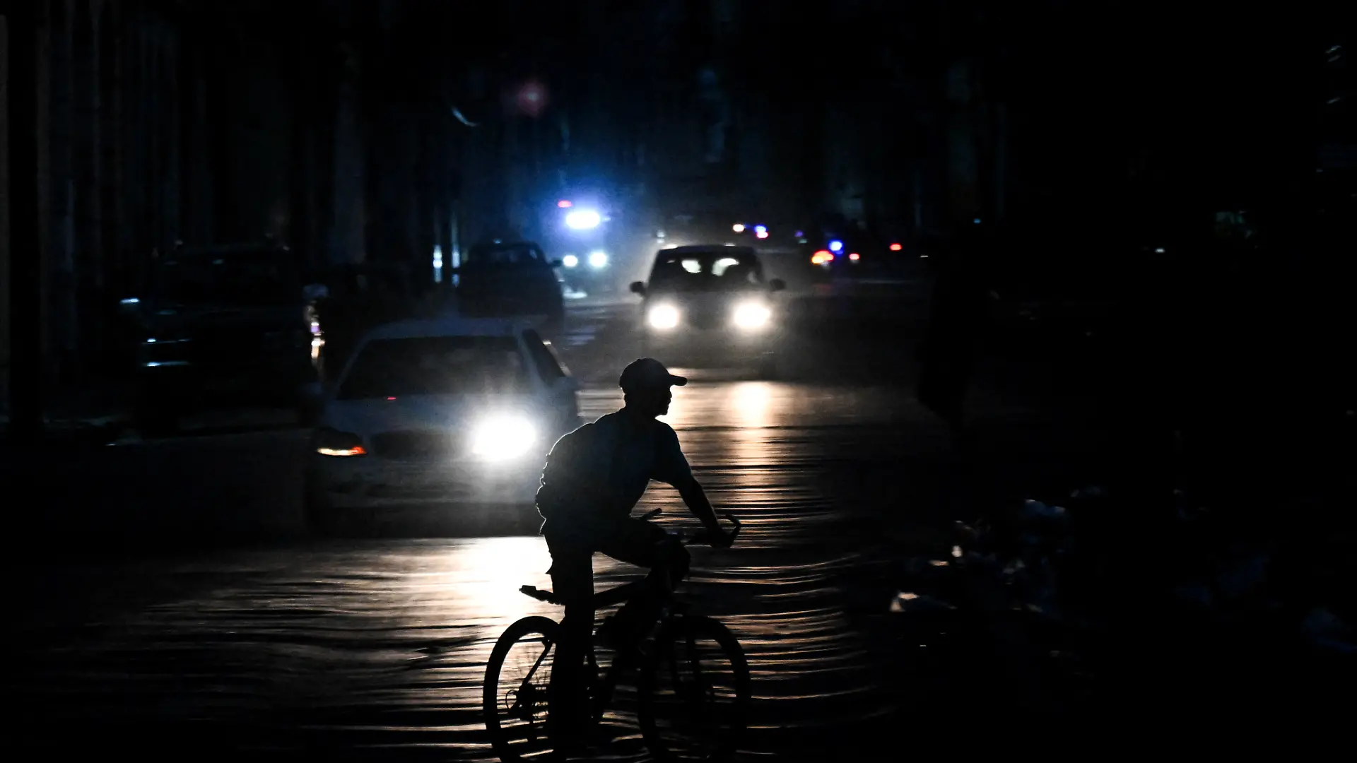 A man rides his bicycle down a street during a blackout in Havana on August 1, 2026. (Photo by YAMIL LAGE / AFP)
