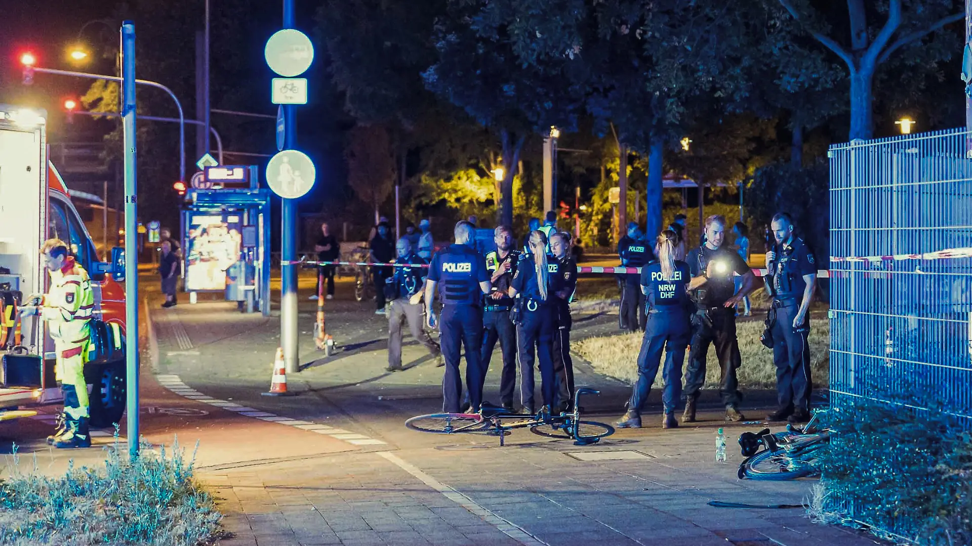Die Polizei und Rettungskräfte sind in Köln Mülheim nach Schüssen auf offener Straße an einem Tatort beschäftigt.