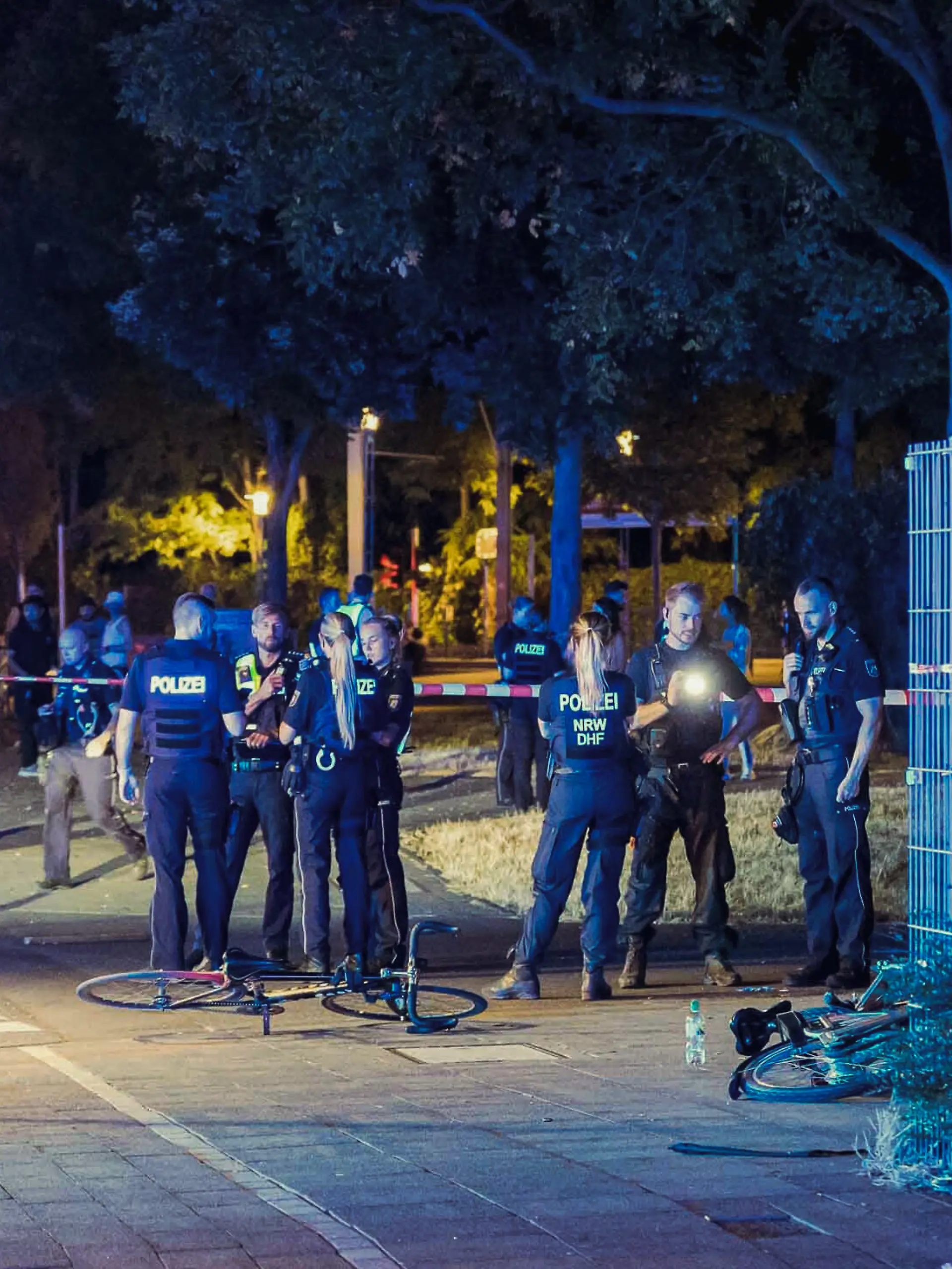 Die Polizei und Rettungskräfte sind in Köln Mülheim nach Schüssen auf offener Straße an einem Tatort beschäftigt.