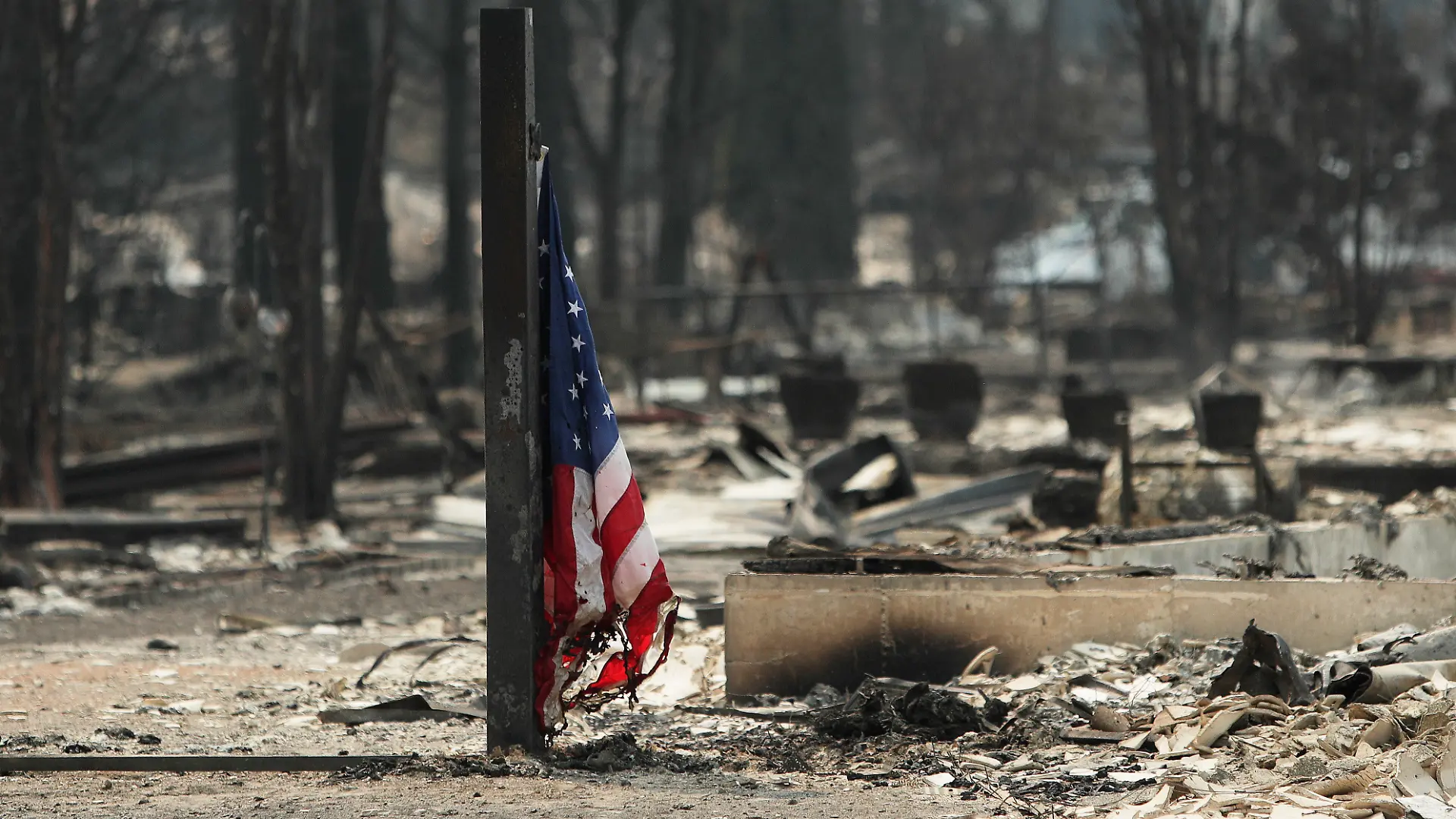 Eine amerikanische Flagge weht vor einem abgebrannten Gebäude in einem Wohngebiet von Westgate nach einem Waldbrand in Spokane, Washington. +++ dpa-Bildfunk +++