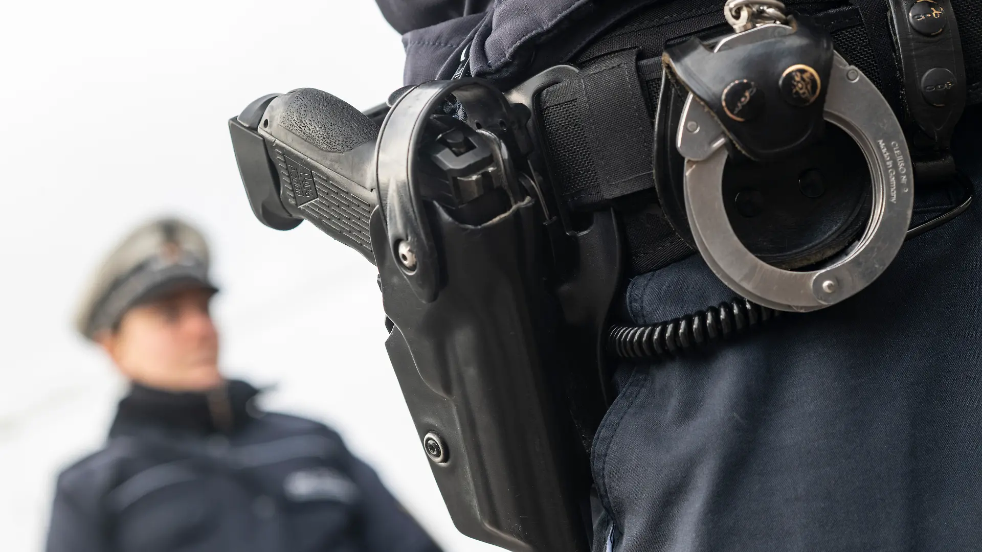 Ein Polizist und eine Polizistin der Polizei Baden-Württemberg stehen in einem Industriegebiet. (gestellte Szene)