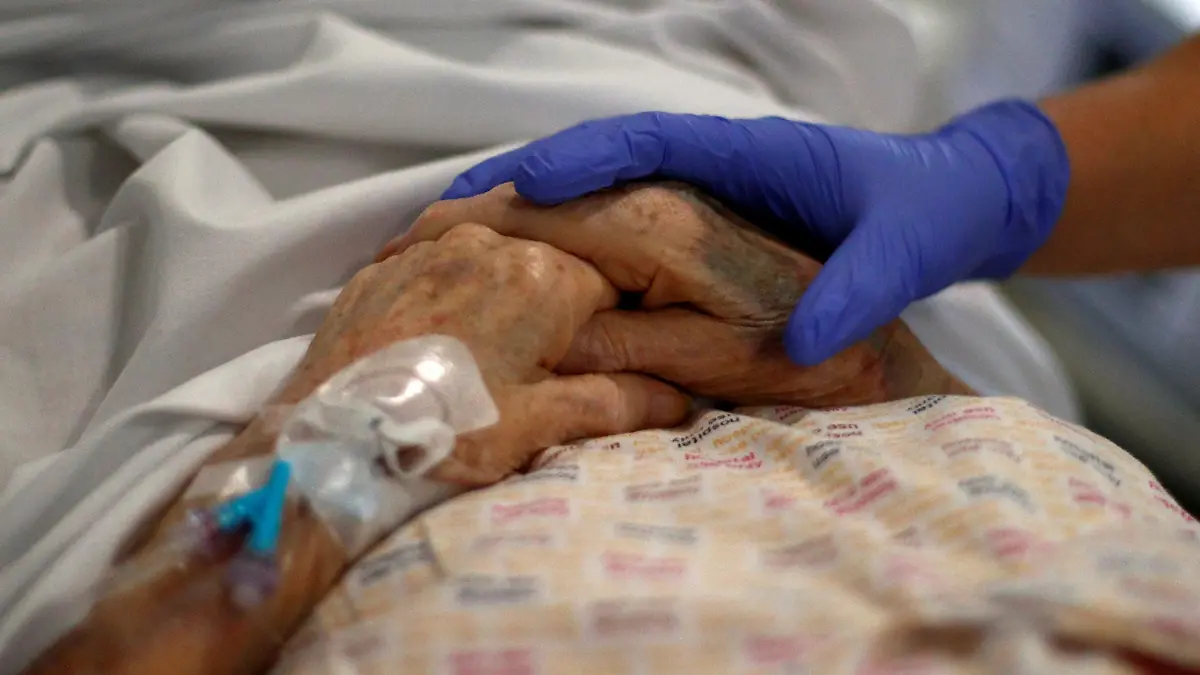 ARCHIV - 17.05.2020, Großbritannien, Blackburn: Ein Radiologe hält die Hand eines Patienten im Royal Blackburn Lehrkrankenhaus, bevor er geröntgt wird. Wegen der Corona-Pandemie warten so viele Menschen wie nie zuvor in England auf eine Behandlung im Krankenhaus. Foto: Hannah Mckay/PA Wire/dpa +++ dpa-Bildfunk +++