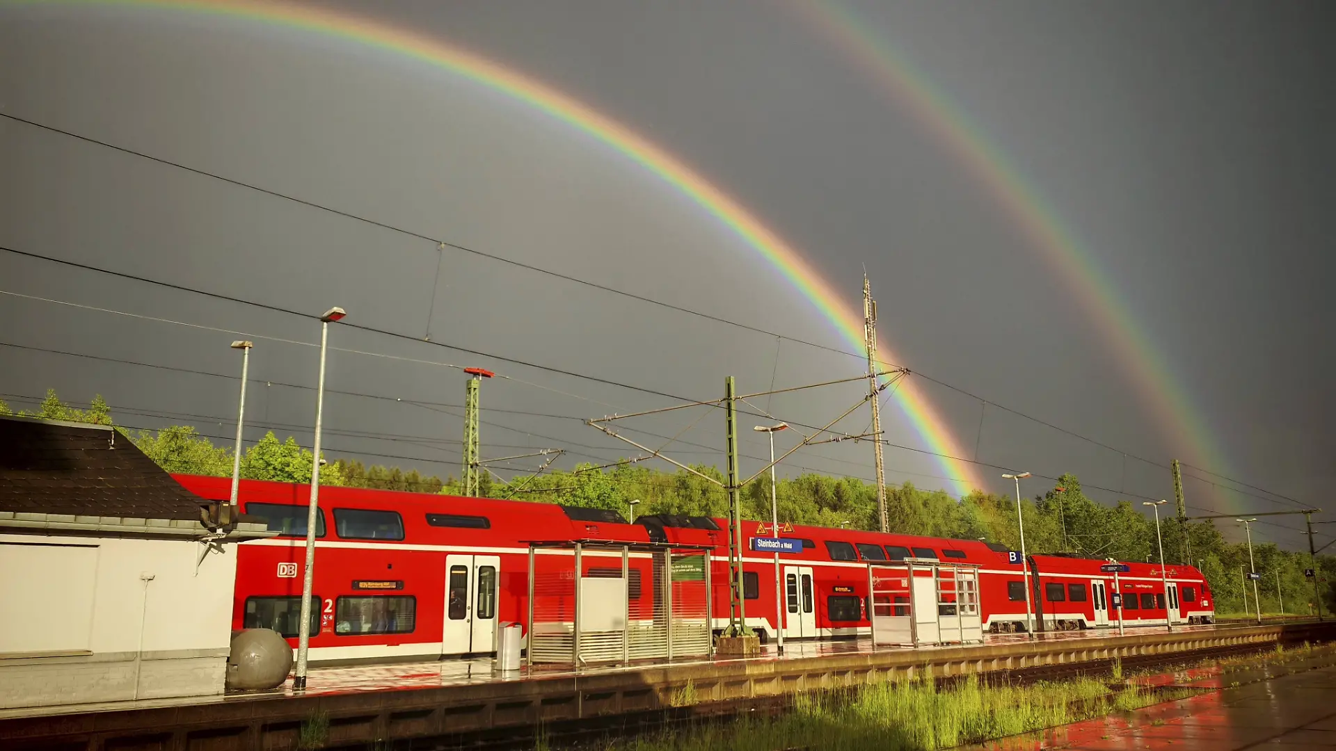 Roter RegionalZug am Bahnhof mit doppeltem Regenbogen über Gleisen und bewölktem Himmel, Steinbach am Wald, Rennsteig, Naturpark Frankenwald Red regional train at train station with double rainbow over tracks and cloudy sky, Steinbach am Wald, Rennsteig, Frankenwald nature park Park Copyright: imageBROKER/MarcoxBunk iblmbu17770515.jpg Bitte beachten Sie die gesetzlichen Bestimmungen des deutschen Urheberrechtes hinsichtlich der Namensnennung des Fotografen im direkten Umfeld der Veröffentlichung