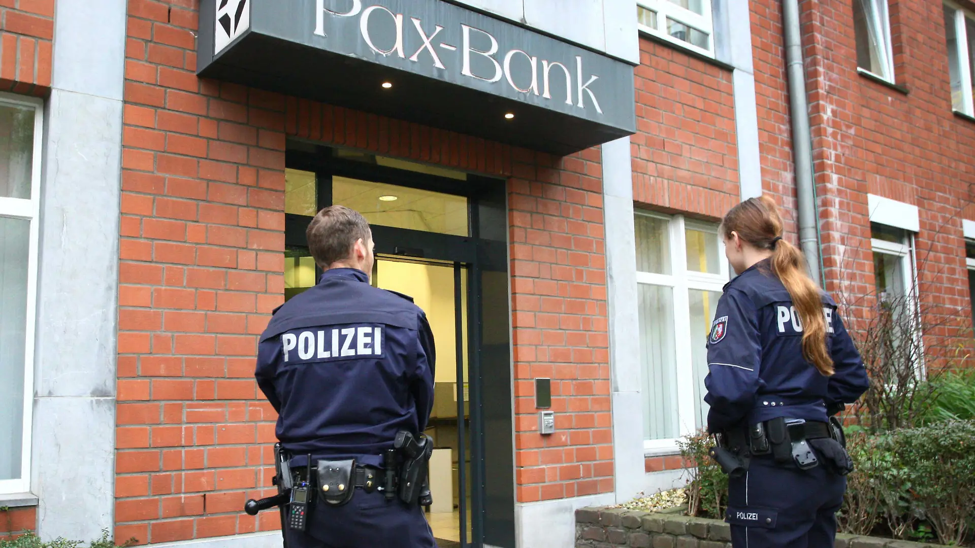 Einsatzkräfte stehen am 19.11.2014 in Aachen (Nordrhein-Westfalen) vor der Filiale der Pax-Bank. Sechs mit Perücken und Sonnenbrillen maskierte Bankräuber haben am Mittwoch in Aachen 16 Bankangestellte bedroht und sind dann mit ihrer Beute geflohen. Nach Polizeiangaben waren die dunkel gekleideten Räuber vor der offiziellen Öffnung in die Bank eingedrungen. Sie fingen nach und nach eintreffende Angestellte ab und bedrohten zuletzt 16 Beschäftigte. Einige davon seien gefesselt worden, sagte Polizeisprecher Werner Schneider. Mindestens eine Schusswaffe sei im Spiel gewesen. Foto: Ralf Roeger/dpa ++ +++ dpa-Bildfunk +++