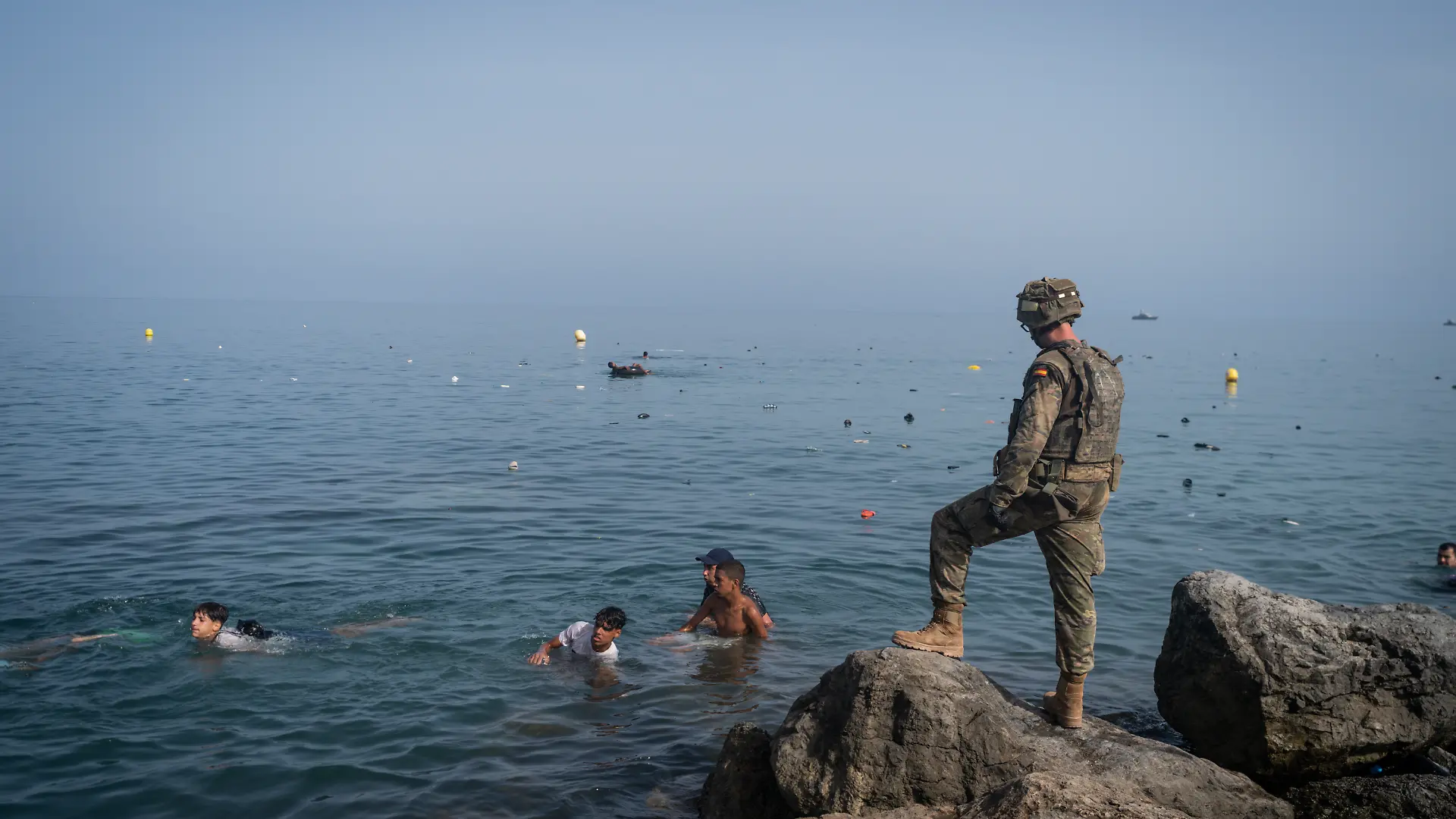 CEUTA, SPAIN - JULY 31: A member of the armed services watches over migrants crossing the border between Spain and Morocco on July 31, 2026 in Ceuta, Spain. Spain's interior ministry has said it's deploying 60 members of the armed forces and an additional 30 Guardia Civil officers to Ceuta after tens of thousands of migrants entered the Spanish enclave in North Africa on Thursday. A large number of people swam through the Tarajal breakwater to enter the Spanish territory from neighboring Morocco, while others scaled the border fence. Some estimates have said that around 49,000 migrants made the crossing, with the surge of arrivals overwhelming migrant reception centres, with many sleeping on the streets overnight. (Photo by Adri Salido/Getty Images)