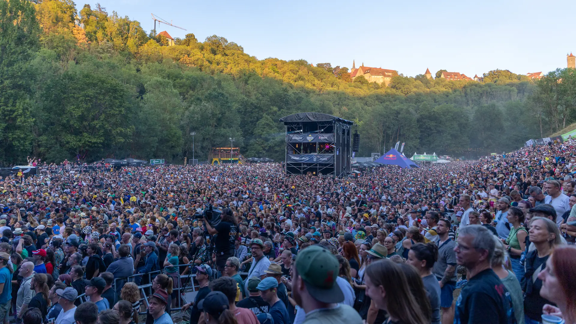 Publikum und Festival-Atmosphäre beim Taubertal-Festival 2026 in Rothenburg ob der Tauber, Deutschland, am 7. August 2026. Bühne mit Künstler. Historische Stadt Rothenburg ob der Tauber im Hintergrund.