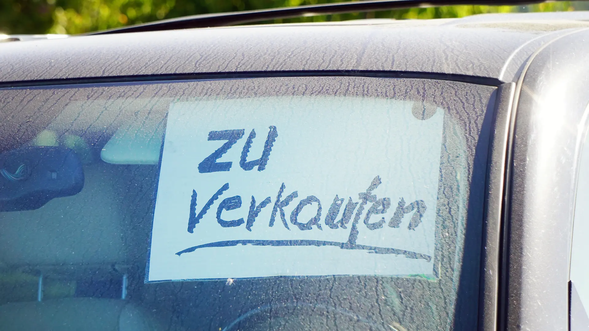 Auto zu verkaufen, Zettel hinter der Windschutzscheibe eines alten schmutzigen PKW