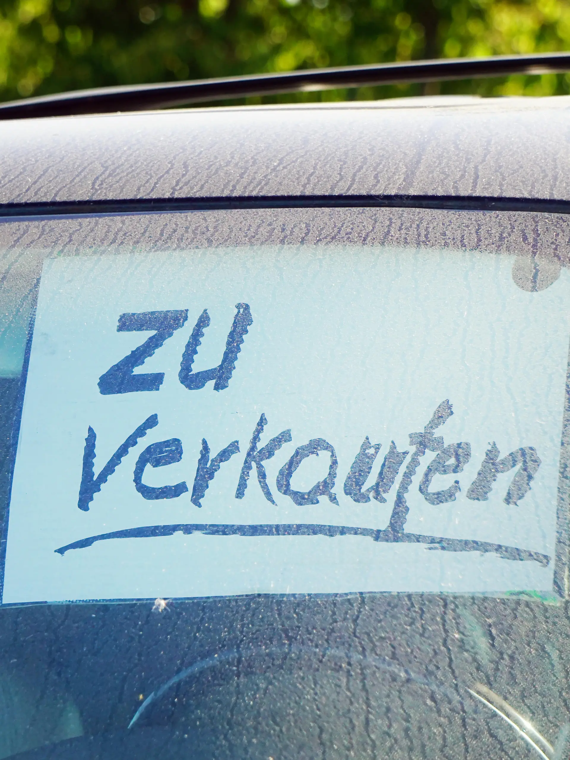 Auto zu verkaufen, Zettel hinter der Windschutzscheibe eines alten schmutzigen PKW
