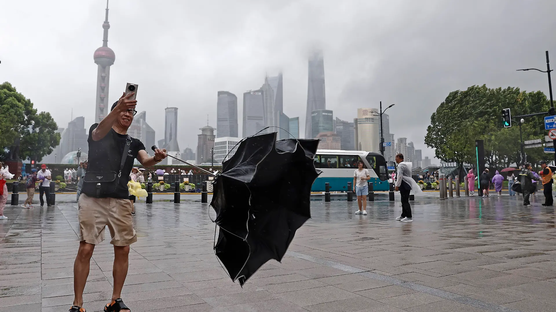 SHANGHAI, CHINA - AUGUST 09: A tourist takes photos with mobile phone while experiencing strong winds on the Bund on August 9, 2026 in Shanghai, China. The Shanghai Meteorological Observatory upgraded the rainstorm warning signal for the central urban area from orange to red at 10:30 a.m. due to the impact of Typhoon Dolphin. PUBLICATIONxNOTxINxCHN Copyright: xChinaxNewsxServicex 111658975464