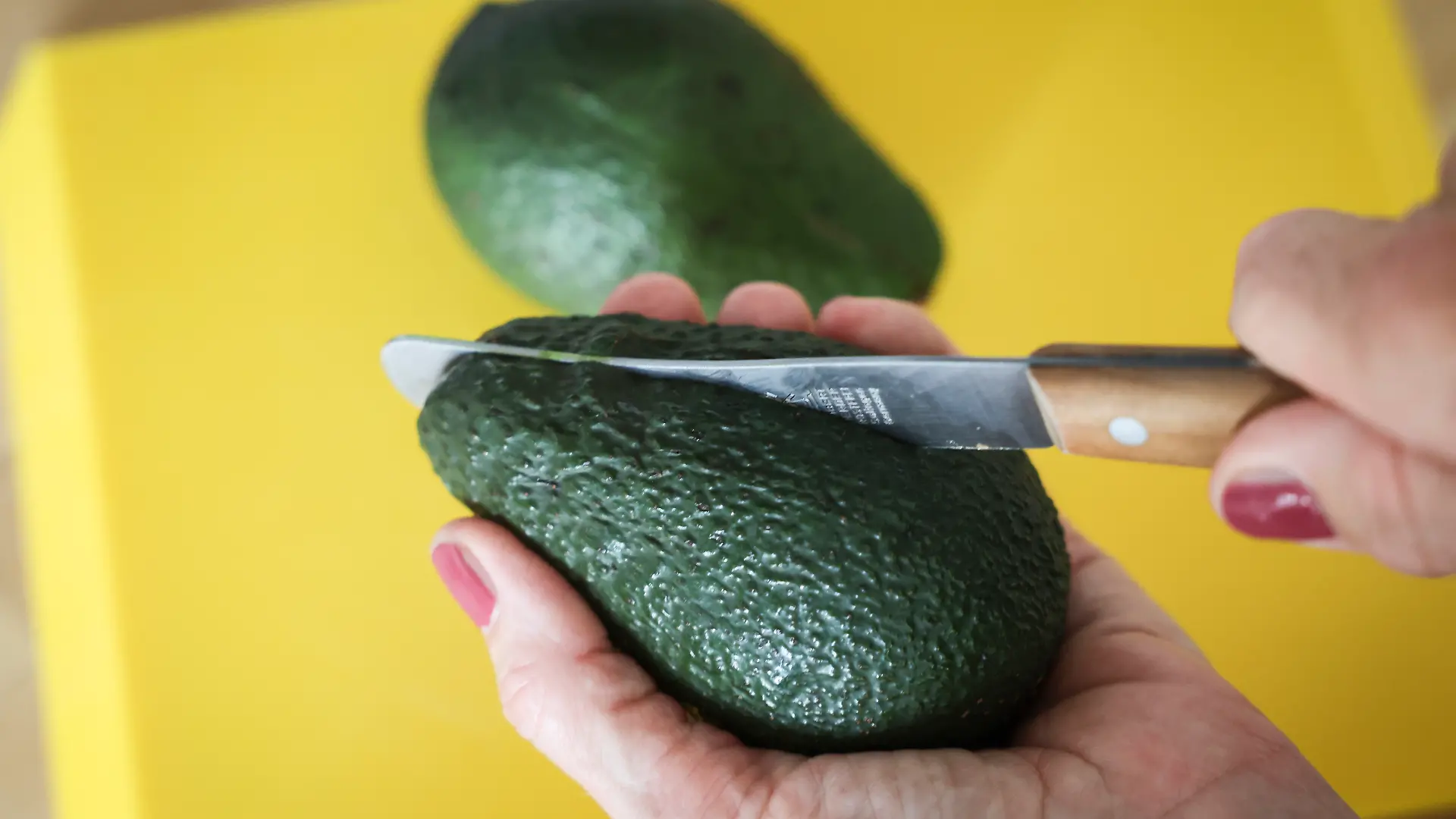 Eine Frau schneidet mit einem Messer eine Avocado auf. Die Zahlen zu Fällen von Schnittverletzungen beim Aufschneiden von Avocados sind gestiegen.