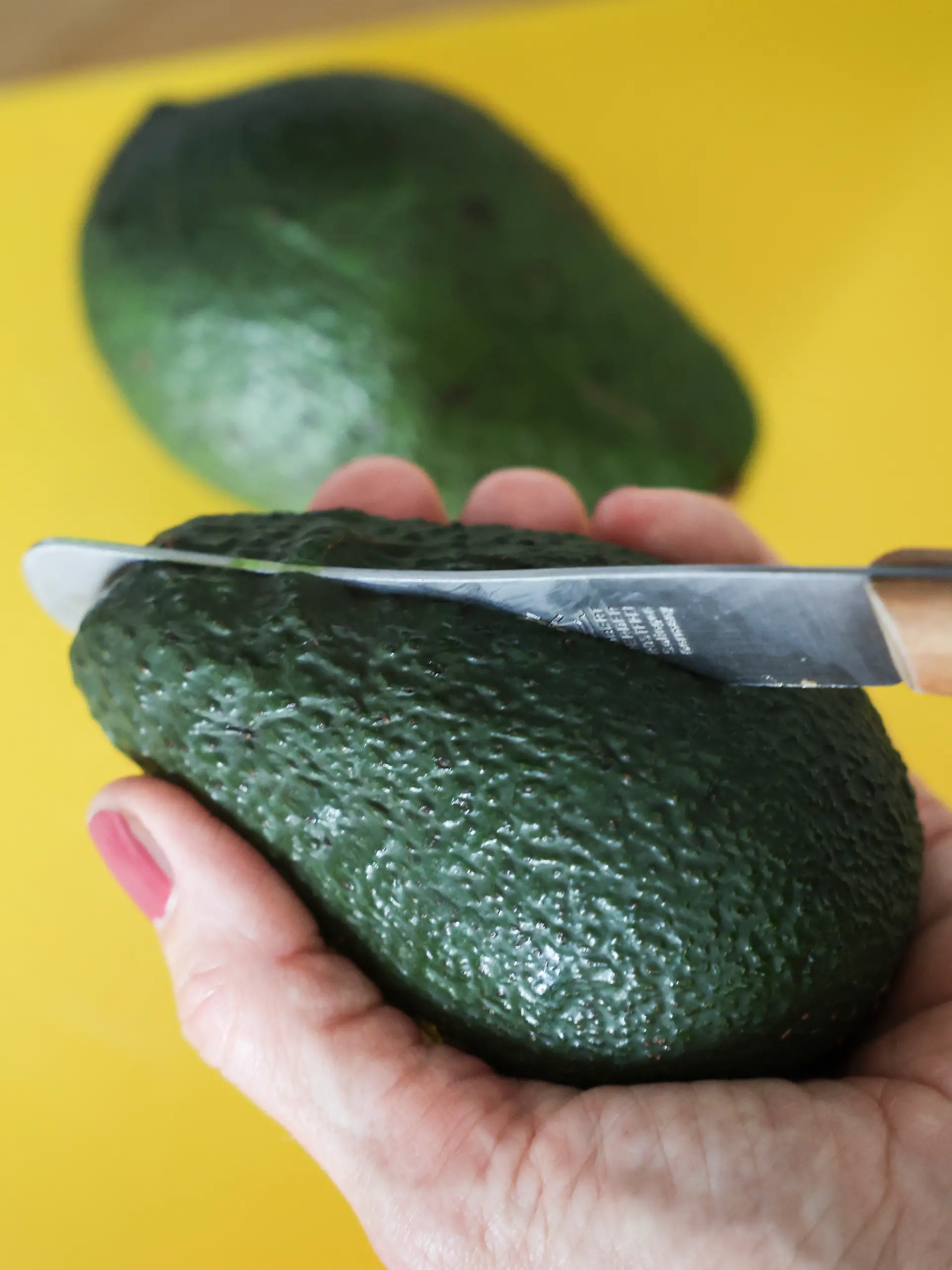 Eine Frau schneidet mit einem Messer eine Avocado auf. Die Zahlen zu Fällen von Schnittverletzungen beim Aufschneiden von Avocados sind gestiegen.