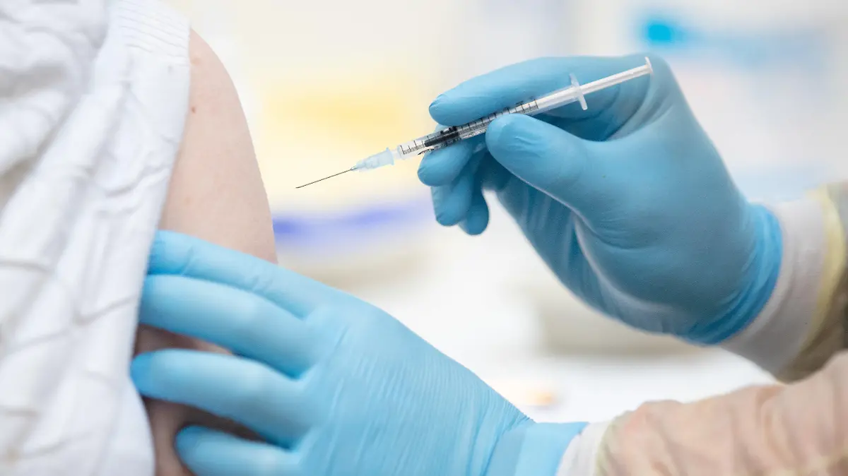 ARCHIV - 01.02.2021, Niedersachsen, Lingen: Eine Person wird im Impfzentrum in den Emslandhallen von einem Notfallsanitäter des DRK (Deutsches Rotes Kreuz) mit dem Wirkstoff von Biontech/Pfizer gegen das Coronavirus geimpft. Das Impftempo in Deutschland zog zuletzt deutlich an · und bald soll es auch für die jüngsten Menschen ganz schnell gehen mit der Impfung gegen das Coronavirus. (zu dpa: "Corona-Impfung bei Kindern - eine Risiko-Nutzen-Abwägung?") Foto: Friso Gentsch/dpa - ACHTUNG: Dieses Foto hat dpa bereits im Bildfunk gesendet +++ dpa-Bildfunk +++