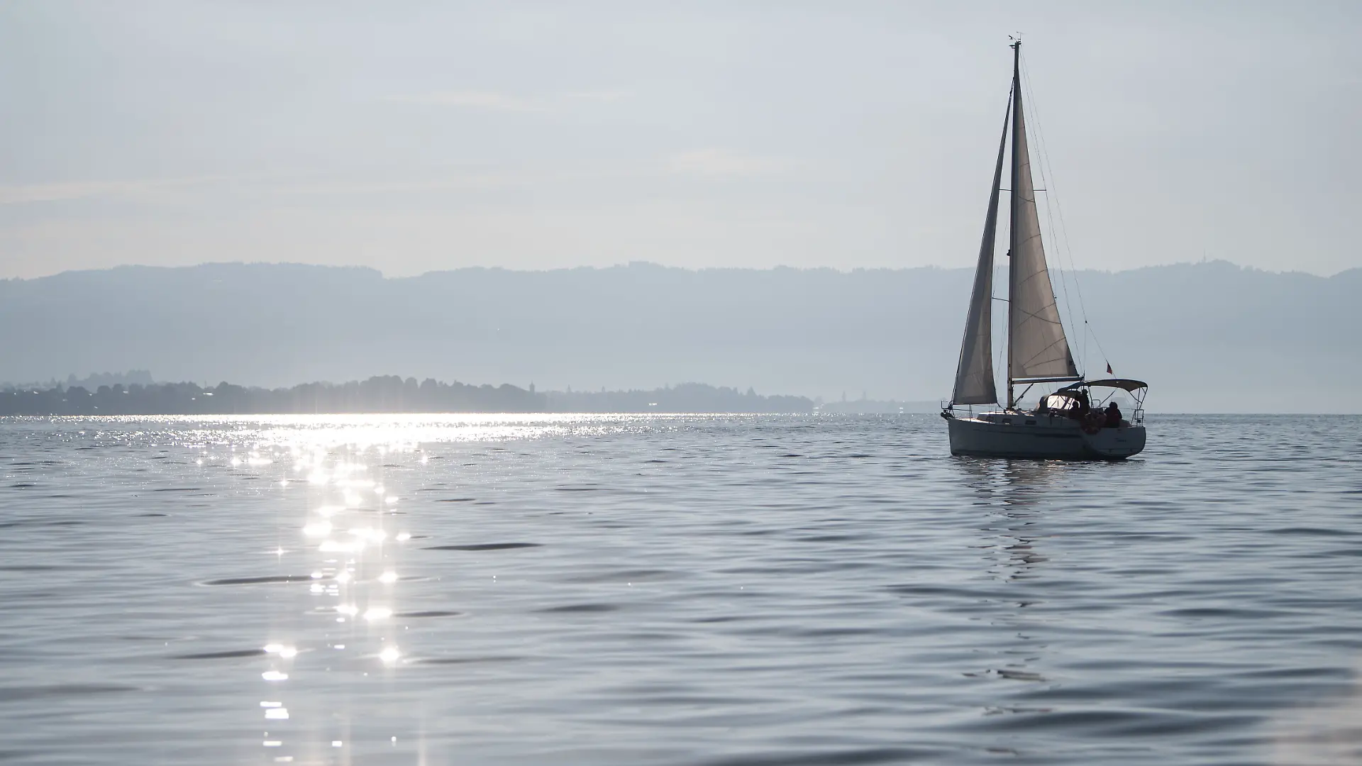 Ein Segelboot fährt auf dem Bodensee, auf dessen Wasser durch die Sonne glitzert. Ein Prozess um ein tödliches Schiffsunglück auf dem Bodensee, bei dem eine 57-jährige Deutsche ums Leben kam, soll neu aufgerollt worden. (zu dpa: «Tod einer Seglerin: 26-Jähriger unter Mordverdacht») +++ dpa-Bildfunk +++