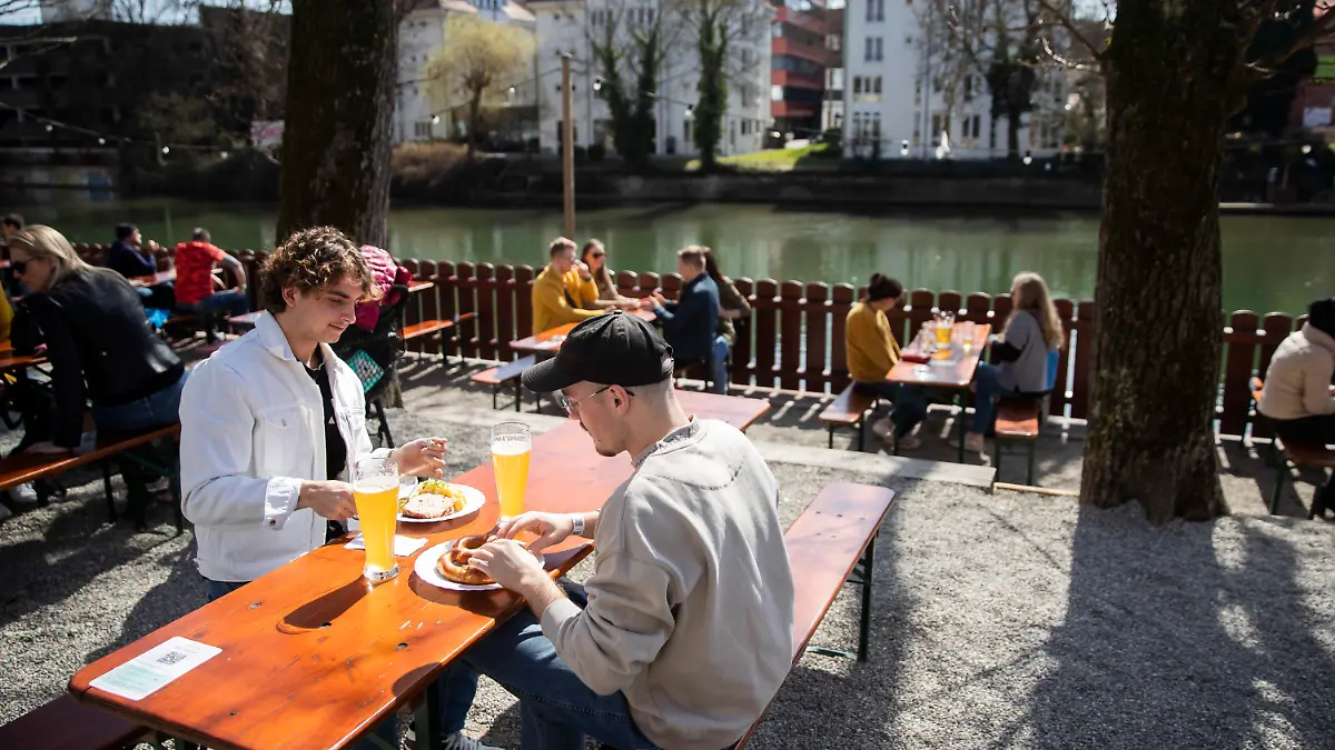 28.03.2021, Baden-Württemberg, Tübingen: Rouven (l) und Rene (r) sitzen bei gutem Wetter in einem Biergarten. In Tübingen können Menschen in der Stadt kostenlose Corona-Tests machen. Mit einem negativen Testergebnis können die getesteten Personen zum Beispiel in Modeläden einkaufen, zum Friseur oder auch in der Außengastronomie bewirtet werden. Foto: Tom Weller/dpa +++ dpa-Bildfunk +++