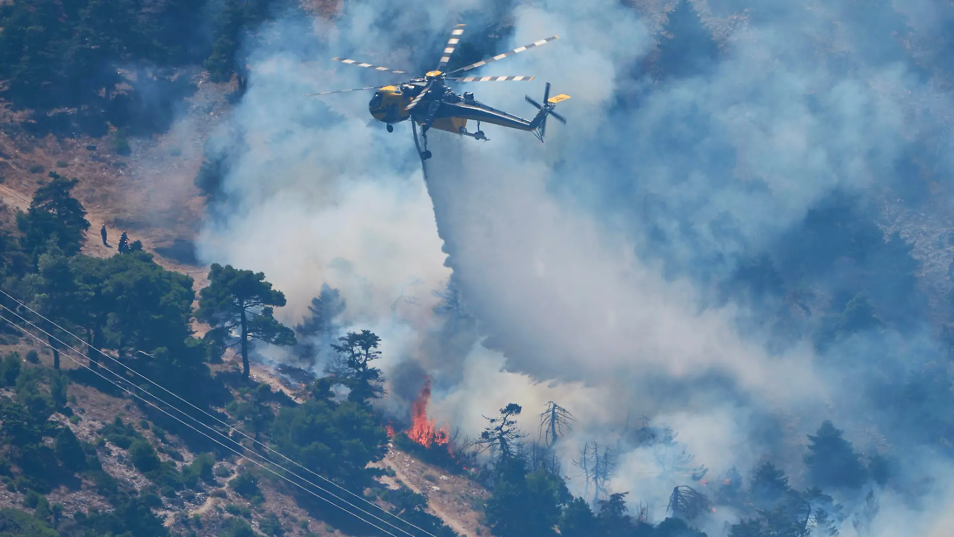 Ein Löschhubschrauber wirft Wasser über einen Waldbrand auf dem Berg Kithairon in der Nähe von Porto Germeno nordwestlich von Athen ab. Die Wald- und Buschbrände westlich der griechischen Hauptstadt sind noch nicht unter Kontrolle. +++ dpa-Bildfunk +++