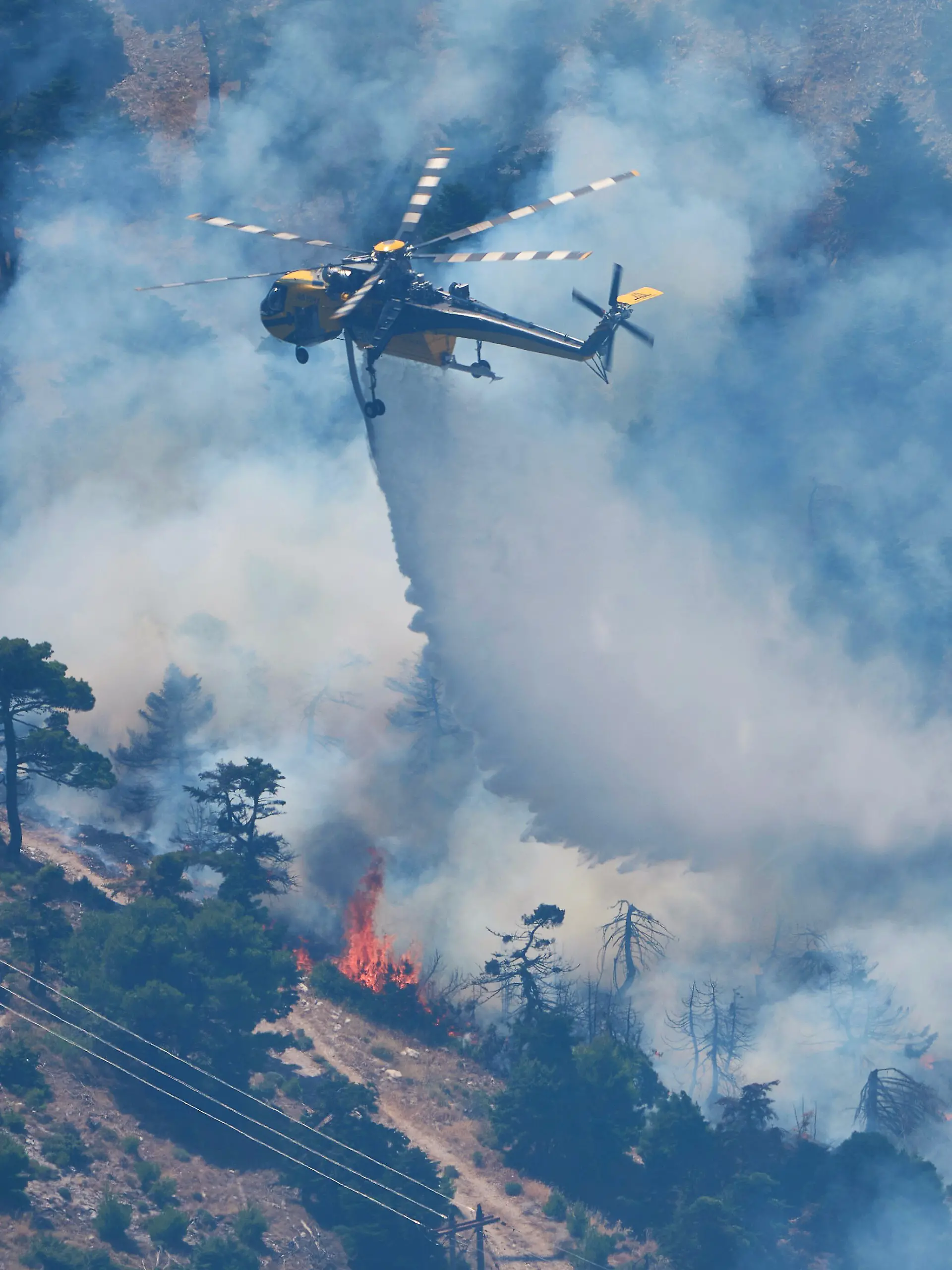 Ein Löschhubschrauber wirft Wasser über einen Waldbrand auf dem Berg Kithairon in der Nähe von Porto Germeno nordwestlich von Athen ab. Die Wald- und Buschbrände westlich der griechischen Hauptstadt sind noch nicht unter Kontrolle. +++ dpa-Bildfunk +++