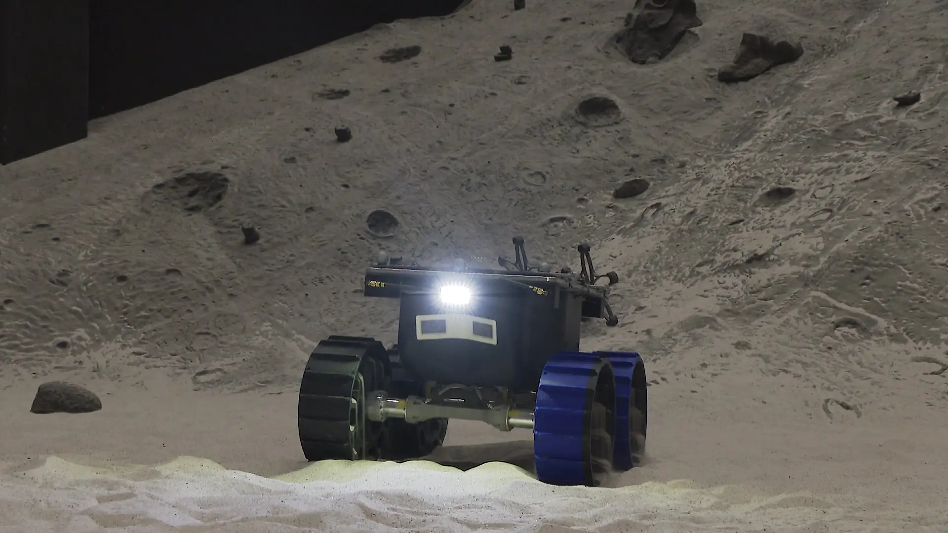 Ein Roboter fährt durch eine künstliche Mondlandschaft.