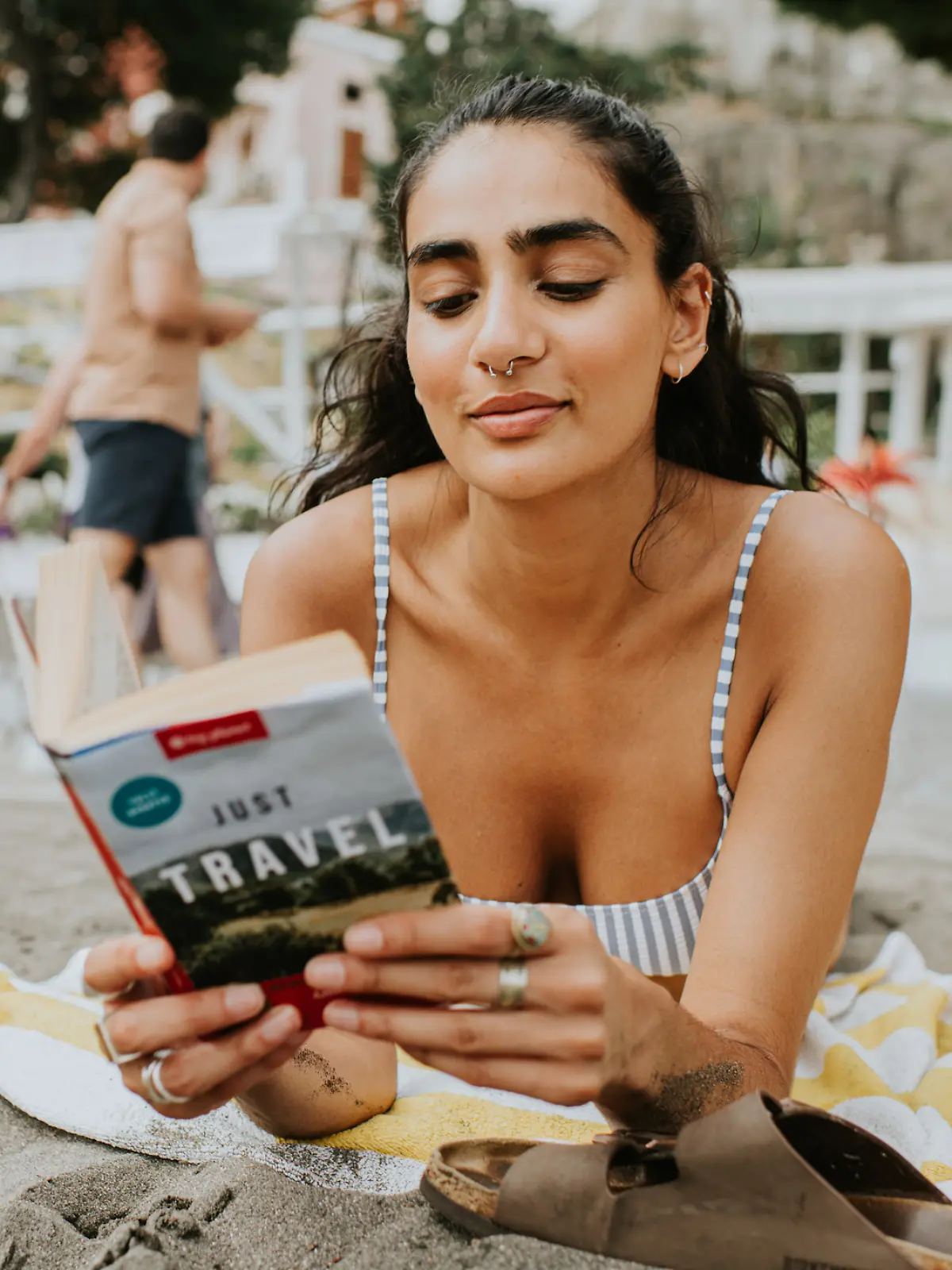Frau liegt alleine am Strand und liest ein Buch