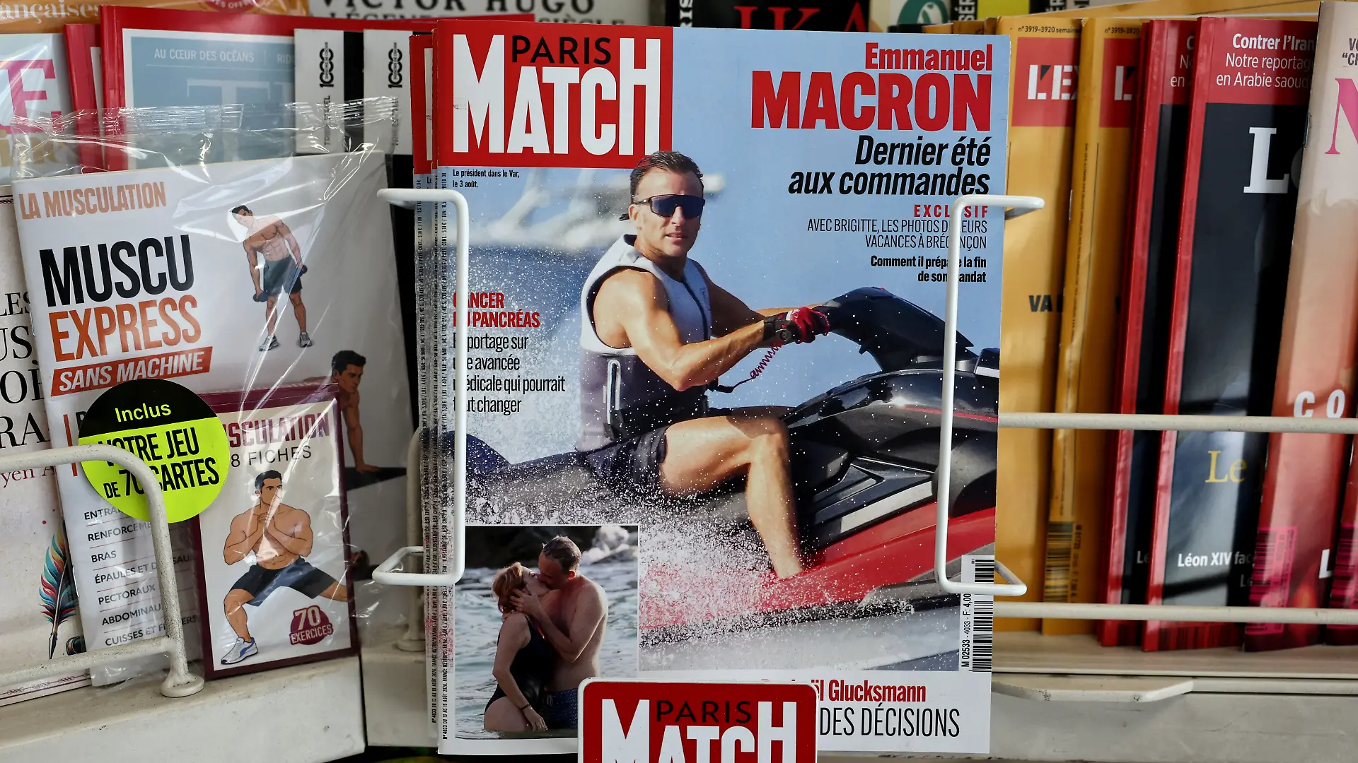This photograph taken in Paris on August 14, 2026 shows the cover of French magazine "Paris Match" depicting France's President Emmanuel Macron on a jet ski during his holiday near the Presidential residence in Bregancon, south-eastern France. Emmanuel Macron is facing a new trial for being out of touch, criticised over a Paris Match feature in which he is photographed enjoying various water activities, including jet skiing, in the middle of a summer marked for the French by successive heatwaves and wildfires. (Photo by SIMON WOHLFAHRT / AFP)
