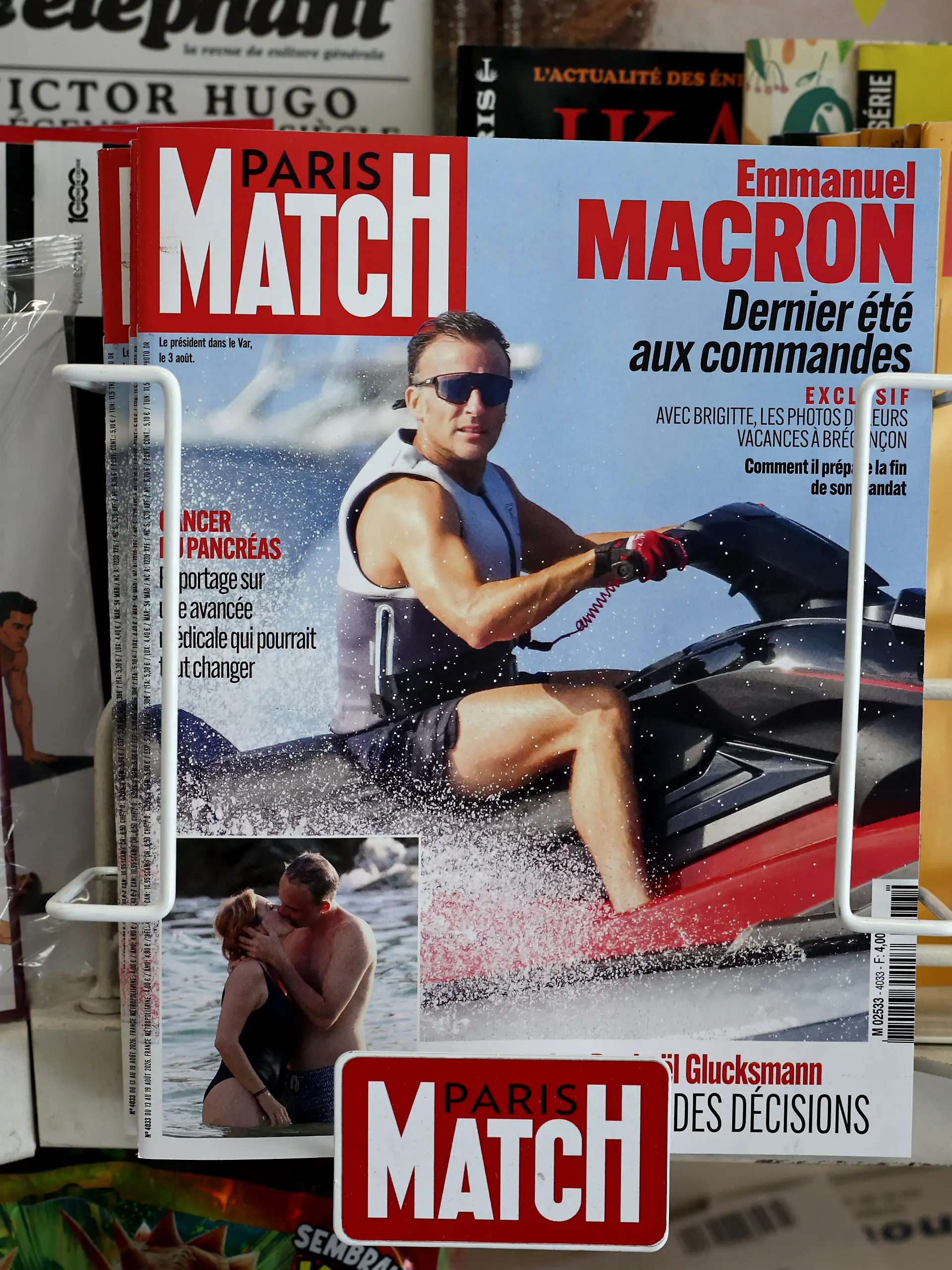 This photograph taken in Paris on August 14, 2026 shows the cover of French magazine "Paris Match" depicting France's President Emmanuel Macron on a jet ski during his holiday near the Presidential residence in Bregancon, south-eastern France. Emmanuel Macron is facing a new trial for being out of touch, criticised over a Paris Match feature in which he is photographed enjoying various water activities, including jet skiing, in the middle of a summer marked for the French by successive heatwaves and wildfires. (Photo by SIMON WOHLFAHRT / AFP)