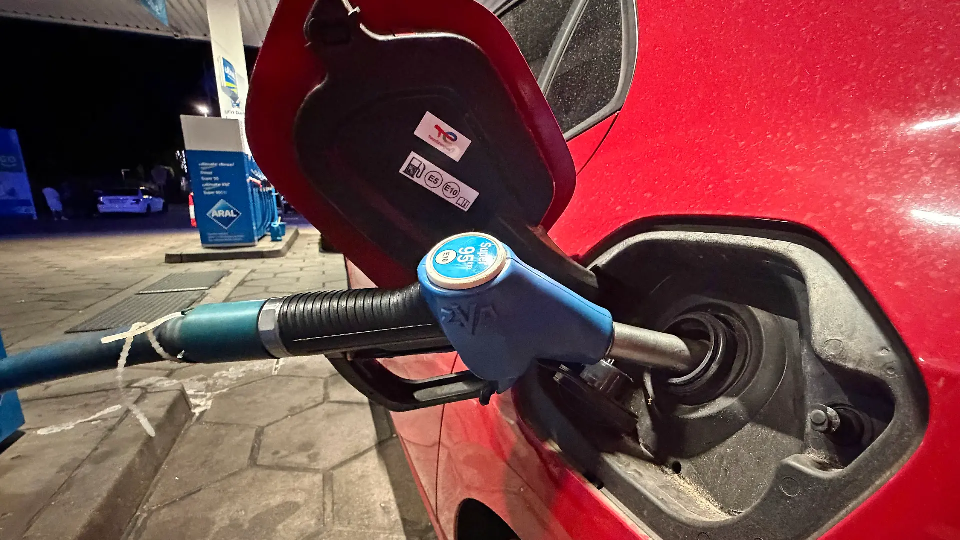 10.08.2026, Wirtschaft v.l. Auf diesem Foto ist ein Tankvorgang an einer Aral-Tankstelle zu sehen. Die Zapfpistole für Super 95 E10 steckt im Tankstutzen eines roten Pkw. Das Motiv kann symbolisch für Benzinpreise, steigende Spritkosten, Kraftstoffversorgung, Tanken und Mobilitätskosten stehen.