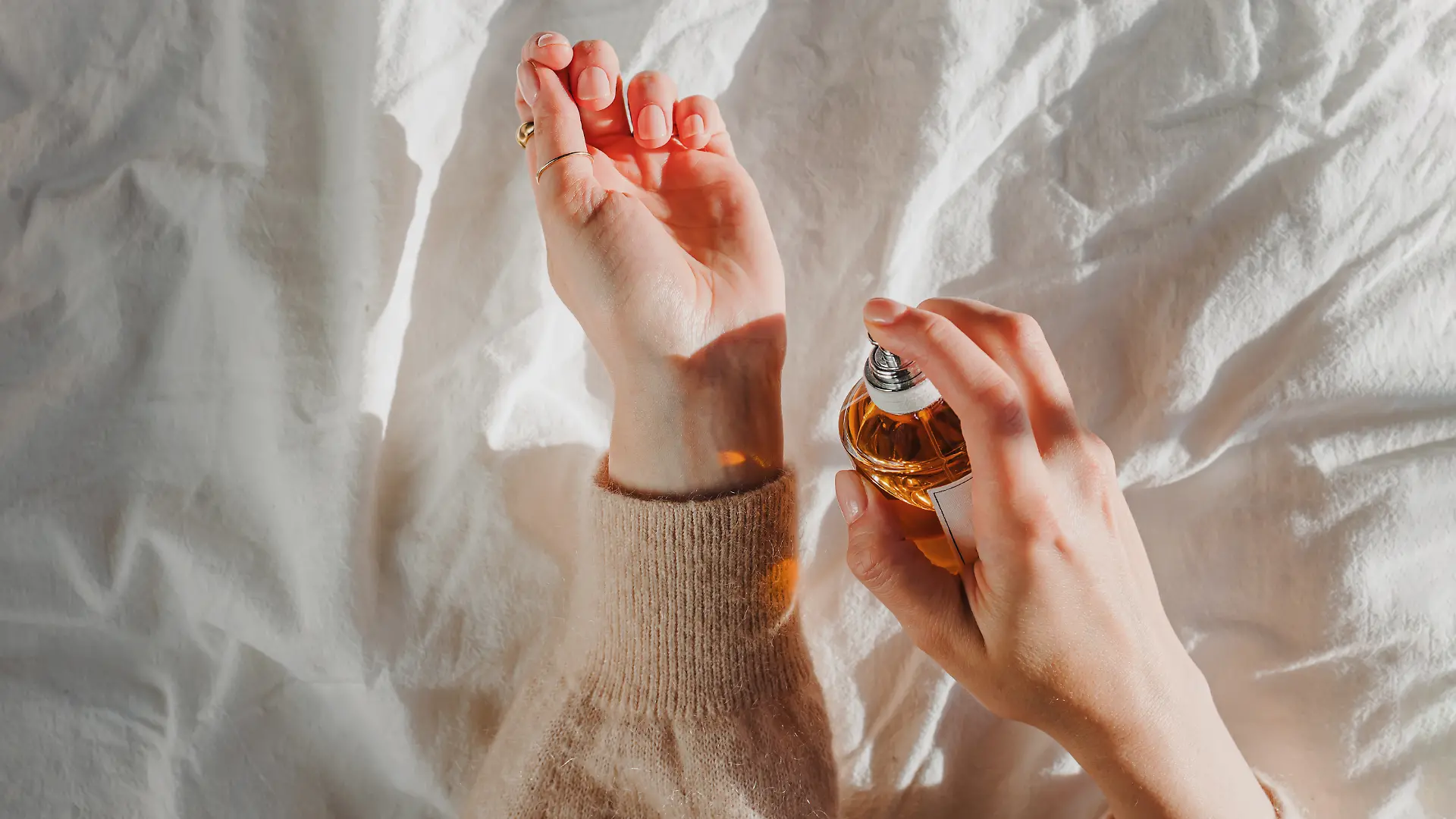 Nahaufnahme: Frau trägt sich Parfum auf das Handgelenk auf.