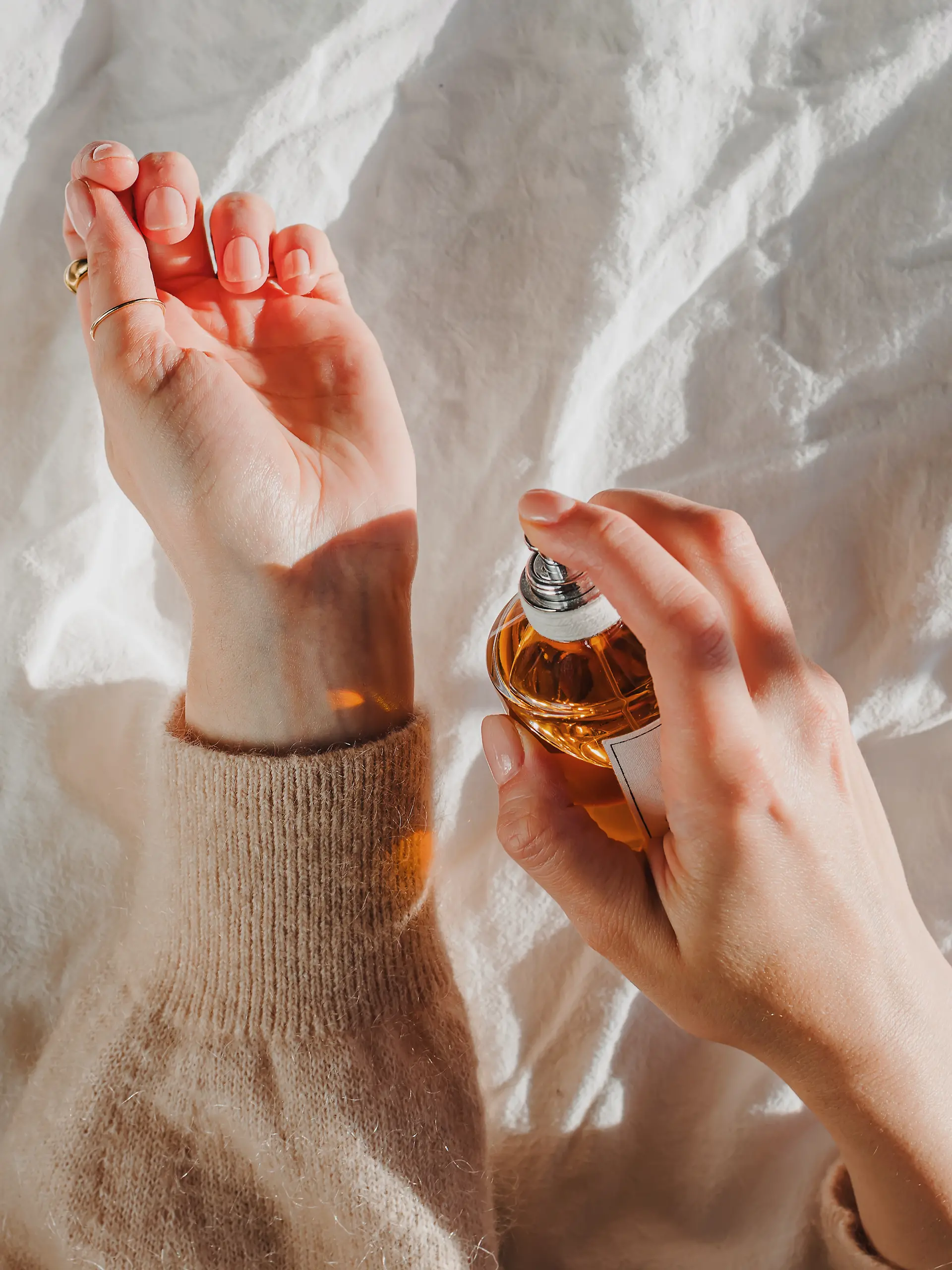 Nahaufnahme: Frau trägt sich Parfum auf das Handgelenk auf.