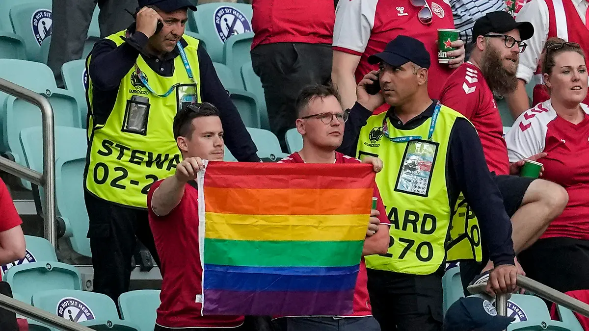 03.07.2021, Aserbaidschan, Baku: Fußball: EM, Tschechien - Dänemark, Finalrunde, Viertelfinale im Baku Olympic Stadium. Ordner stehen neben zwei Dänemark Fans die eine Regenbogen-Fahne hochhalten. Foto: Darko Vojinovic/Pool AP/dpa +++ dpa-Bildfunk +++