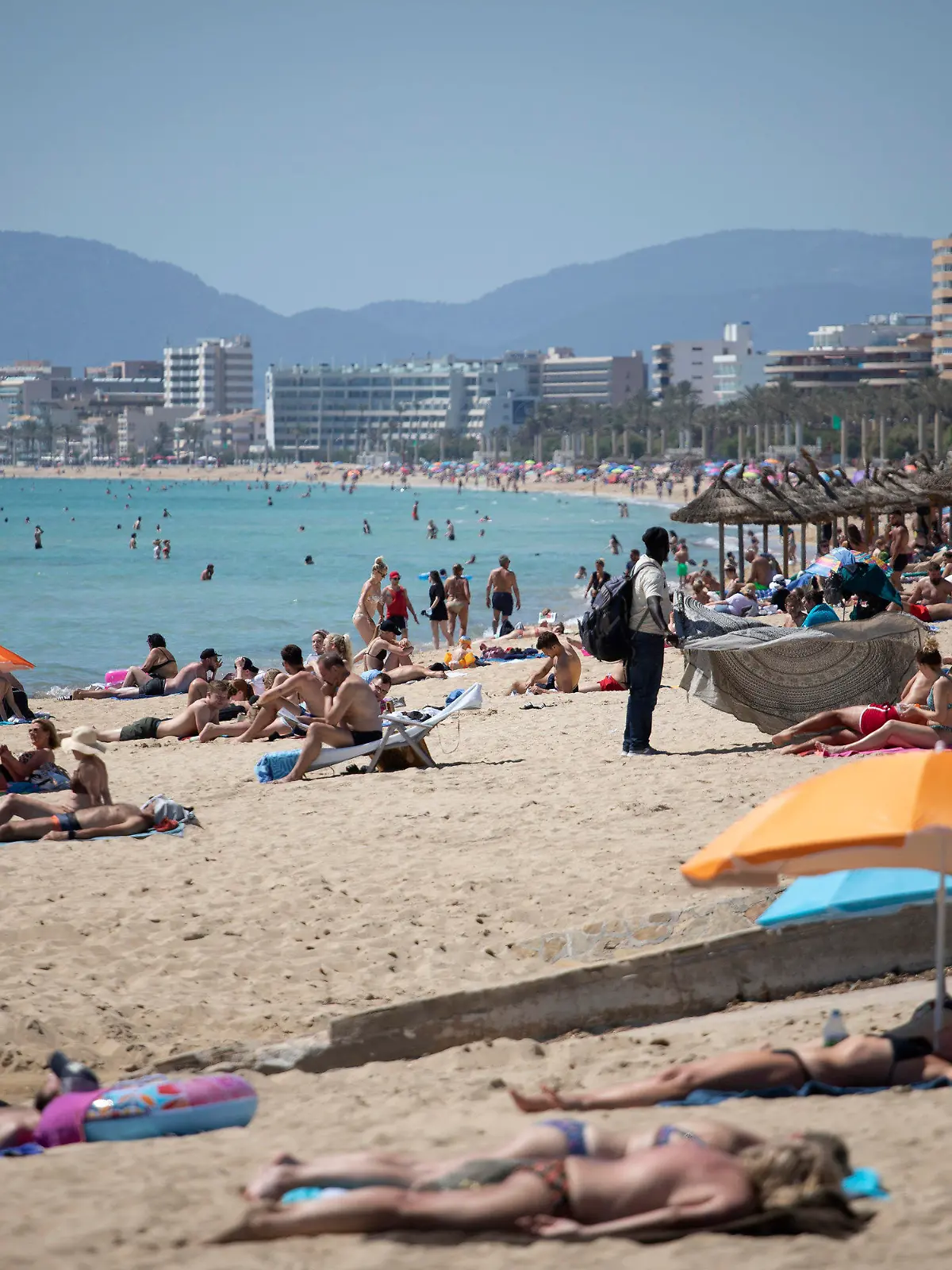07.06.2021, Spanien, Mallorca: Touristen genießen die Sonne an einem Strand auf der spanischen Insel Mallorca. Landesweit startet die Sommertourismus-Saison mit coronabedingten Einschränkungen. Einreisende müssen vollständig geimpft sein oder, wenn sie aus Europa kommen, einen aktuellen negativen Corona-Test vorweisen. Foto: Francisco Ubilla/AP/dpa +++ dpa-Bildfunk +++