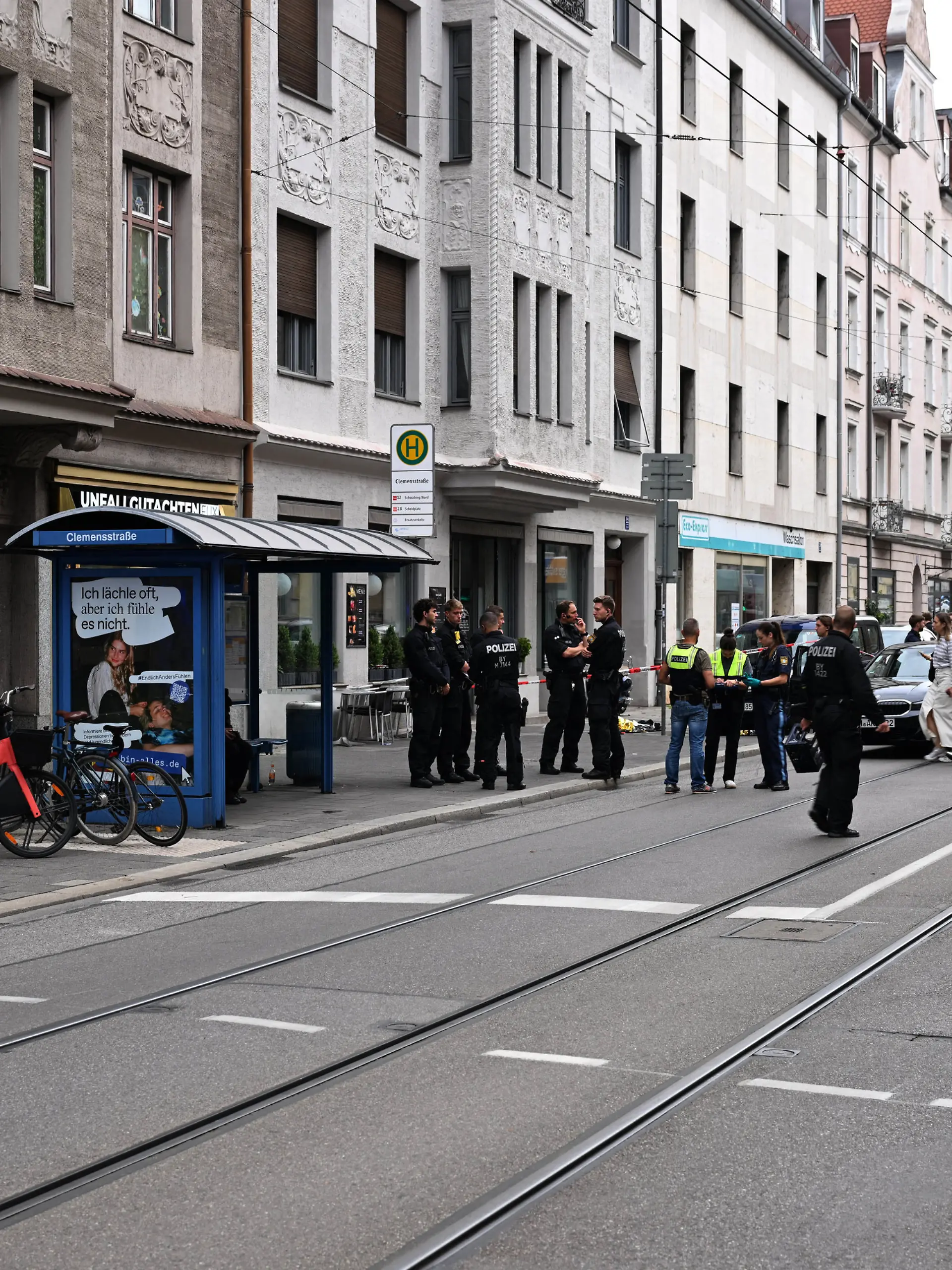 18.08.2026, Bayern, München: Viele Polizisten stehen am Tatort. Im Münchner Stadtteil Schwabing ist es zu einem polizeilichen Schusswaffengebrauch gekommen. Eine Person sei schwer verletzt ins Krankenhaus gebracht worden, berichtete ein Polizeisprecher. Warum geschossen wurde, sei noch unklar, man stehe ganz am Anfang. Foto: Felix Hörhager/dpa +++ dpa-Bildfunk +++