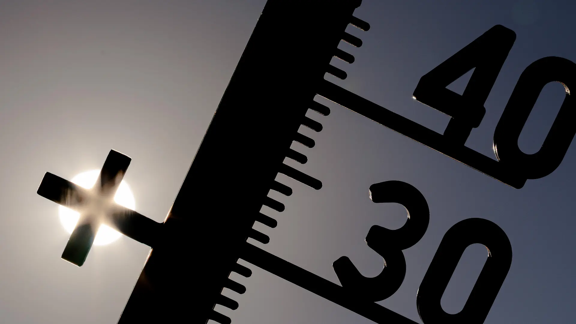 Vor einem wolkenlosen blauen Himmel leuchtet die Sonne hinter dem Pluszeichen eines Außenthermometers, das man auch als Kreuz deuten kann, welches am 14.08.2026 in Lotte-Wersen (Nordrhein-Westfalen, Deutschland) über 36 Grad Lufttemperatur anzeigt. Nach Angaben des Deutschen Wetterdienstes (DWD) und des Robert Koch-Instituts führten langanhaltende Extremtemperaturen und neue Allzeitrekorde im Sommer 2026 zu einer außergewöhnlich hohen hitzebedingten Belastung in ganz Deutschland.