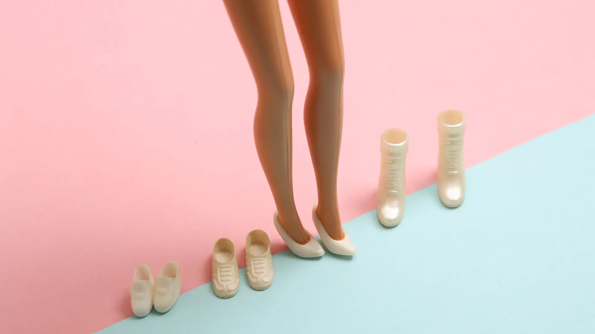 Beine von Barbie umgeben von High Heels, Sneakern und Stiefeln