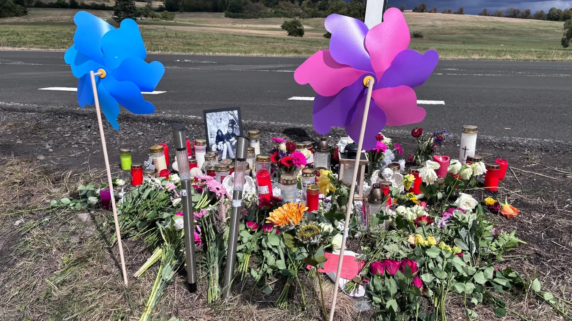 An der Unfallstelle stehen Blumen, Kerzen und bunte Windräder