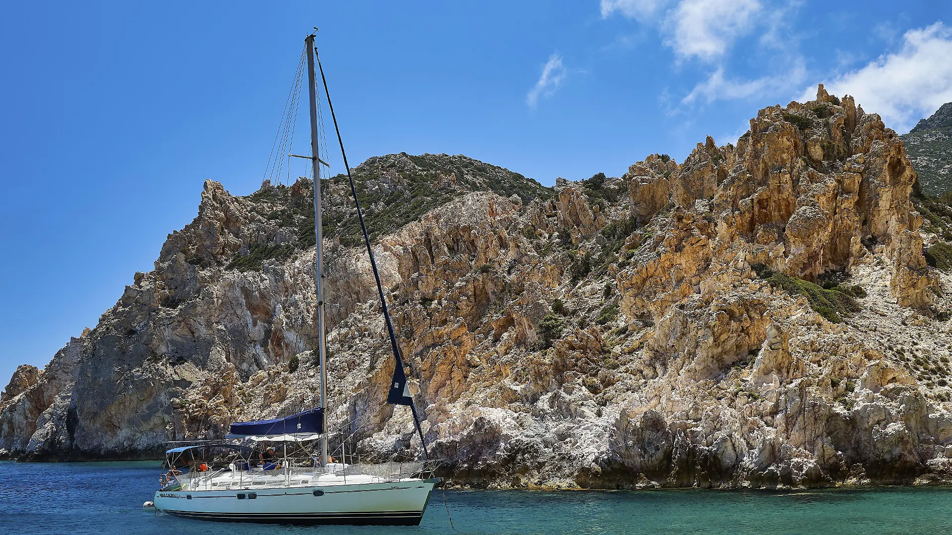 Ammoura-Bucht, Bucht von Ammoura, Segelboot vor schroffen Felsen, das klare blaue Wasser glitzert unter einem sonnigen Himmel, Poliegos, Polyaigos, Insel südöstlich von Kimolos, nordöstlich von Milos, Natura 2000 Region, unbewohnte Insel, Kykladen, Griechische Inseln, Griechenland