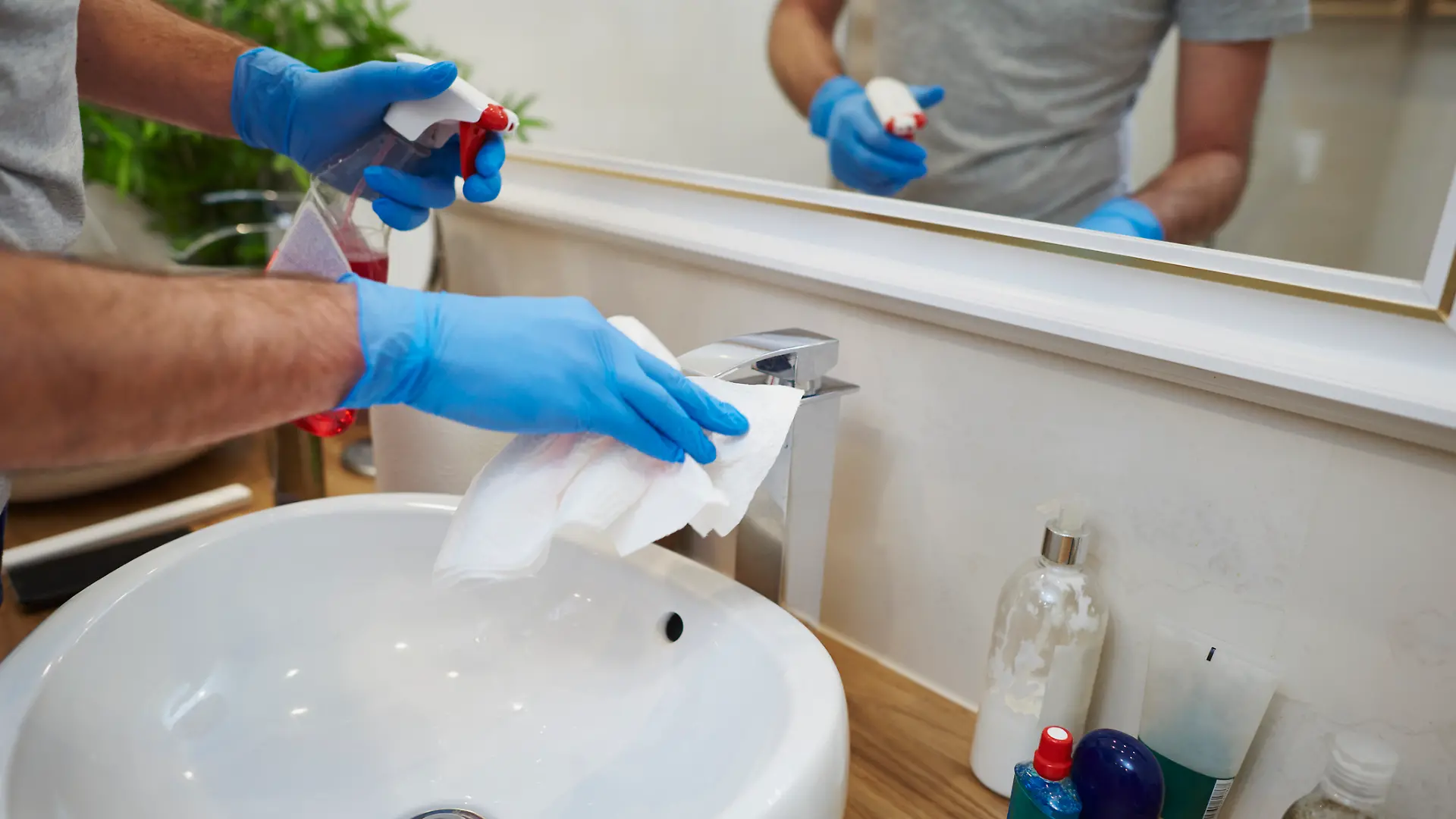Männerhände putzen Waschbecken im Badezimmer