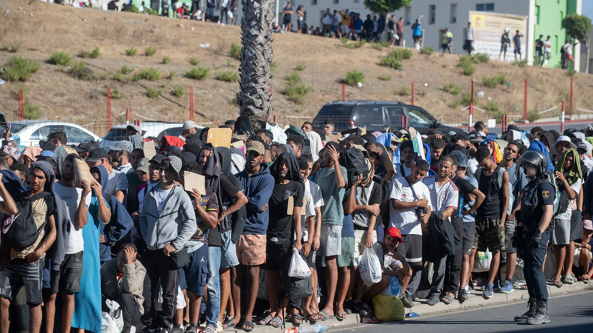 Migrants wait in a queue at the Loma Margarita temporary reception center in Ceuta, Spain on August 24, 2026, where the NGO Accem is providing support to 1,100 migrants at the facility now at full capacity. In the autonomous city, the NGO Engloba manages the Loma Colmenar center with 700 additional places, bringing the total to 1,800 reception center spots established following a mass influx on July 30, 2026. Photo by Marcos Moreno/Europa Press/ABACAPRESS.COM