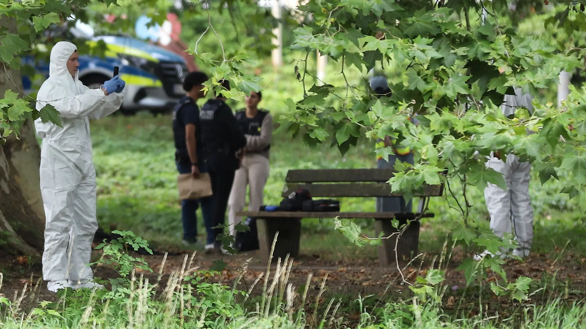 25.08.2026, Nordrhein-Westfalen, Leverkusen: Einsatzkräfte der Polizei in Schutzkleidung arbeiten an einem Tatort, nachdem ein junger Mann mit einer Stichwaffe schwer verletzt worden ist. Die Polizei war mit einem großen Aufgebot von rund 20 Streifenwagen vor Ort im Einsatz. Foto: -/dpa +++ dpa-Bildfunk +++