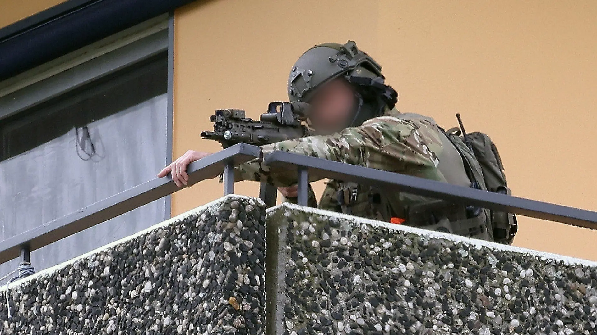 11.05.2023, Ratingen: Ein Polizeibeamter in Spezialausrüstung steht auf einem Balkon und zielt mit einer Waffe. Bei einer Explosion in einem Hochhaus in Ratingen am Donnerstagvormittag wurden mehrere Menschen verletzt - darunter auch Polizisten und Einsatzkräfte der Feuerwehr. Das erfuhr die Deutsche Presse-Agentur aus Polizeikreisen. Foto: David Young/dpa - ACHTUNG: Die Person wurde aus rechtlichen Gründen gepixelt +++ dpa-Bildfunk +++