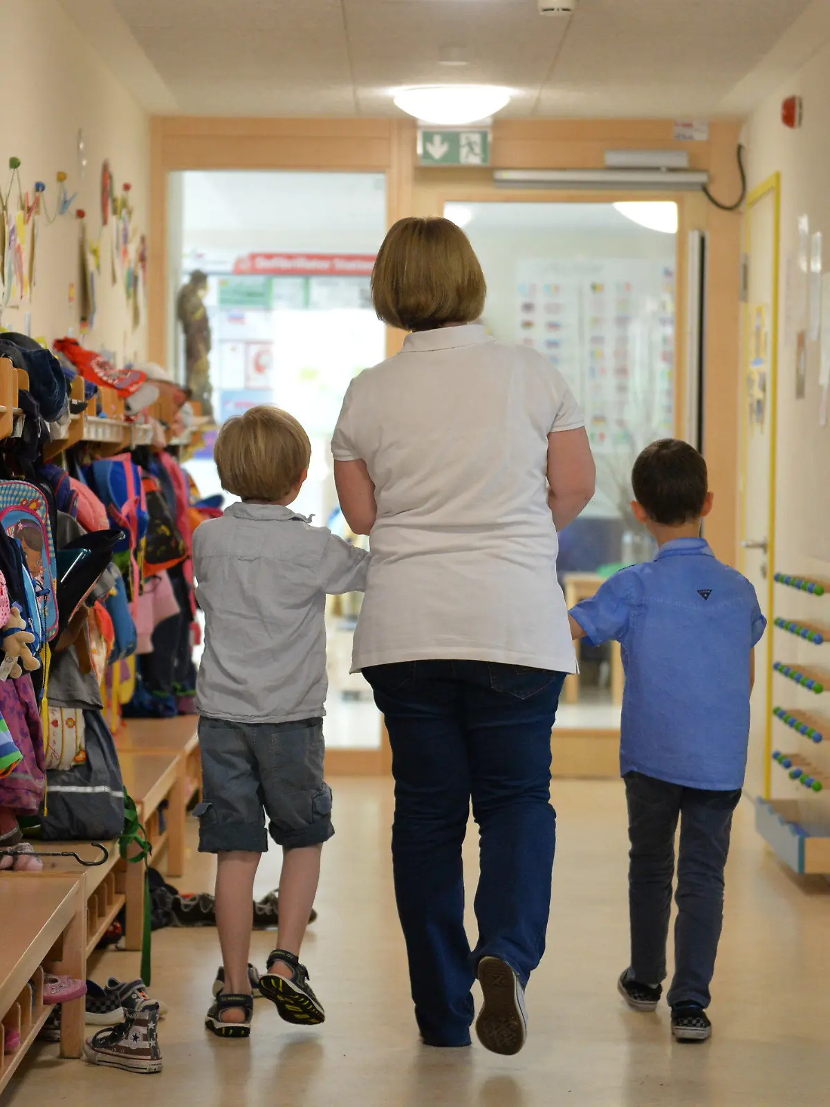 ARCHIV - 21.06.2016, Baden-Württemberg, Leinfelden-Echterdingen: Eine Erzieherin geht im St. Michaels Kindergarten in Leinfelden-Echterdingen mit zwei Kindern über den Flur der Einrichtung.   (zu dpa: «Vertragsunterzeichnung «Gute-Kita-Gesetz»») Foto: Jan-Philipp Strobel/dpa +++ dpa-Bildfunk +++