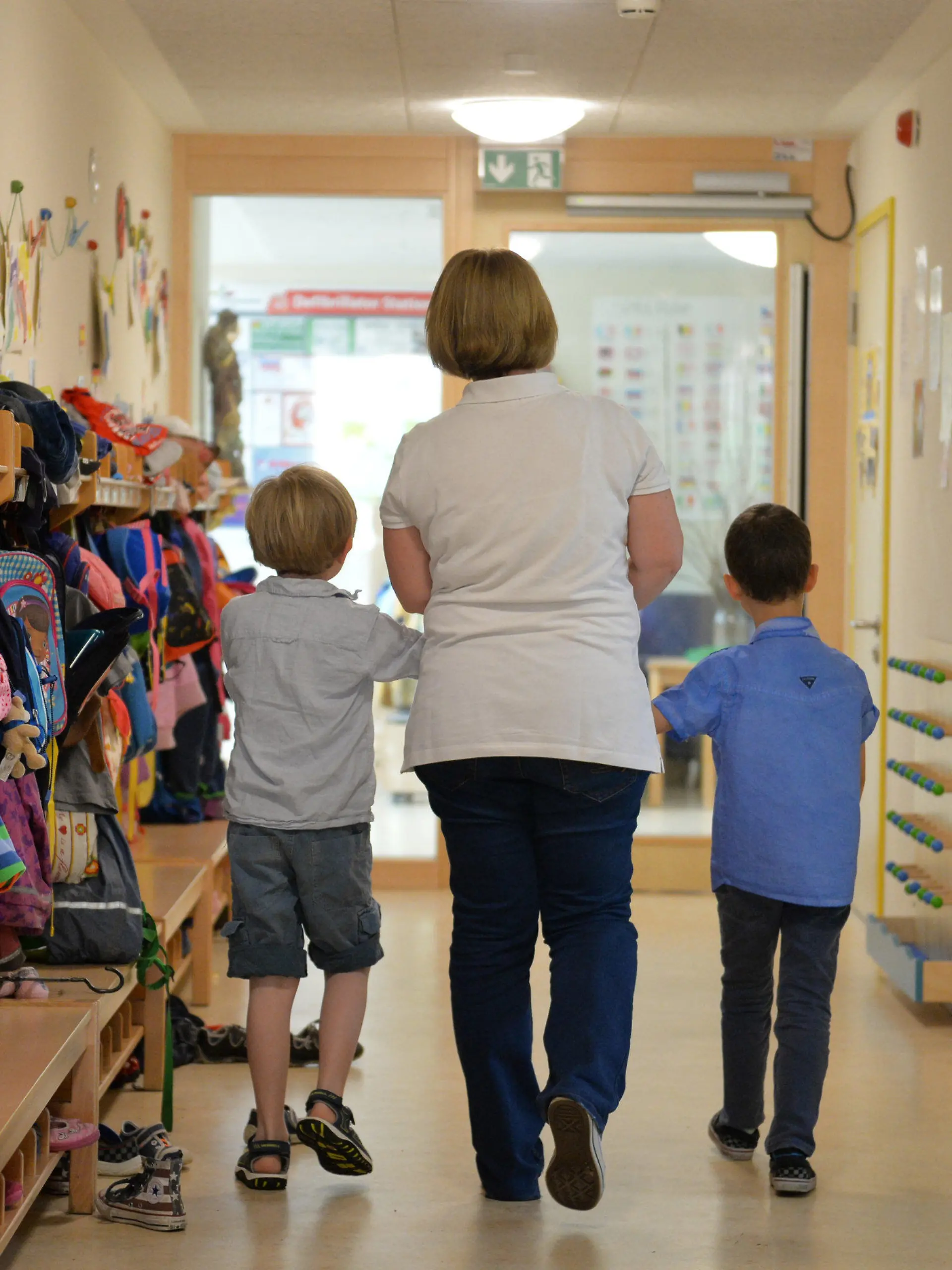 ARCHIV - 21.06.2016, Baden-Württemberg, Leinfelden-Echterdingen: Eine Erzieherin geht im St. Michaels Kindergarten in Leinfelden-Echterdingen mit zwei Kindern über den Flur der Einrichtung.   (zu dpa: «Vertragsunterzeichnung «Gute-Kita-Gesetz»») Foto: Jan-Philipp Strobel/dpa +++ dpa-Bildfunk +++