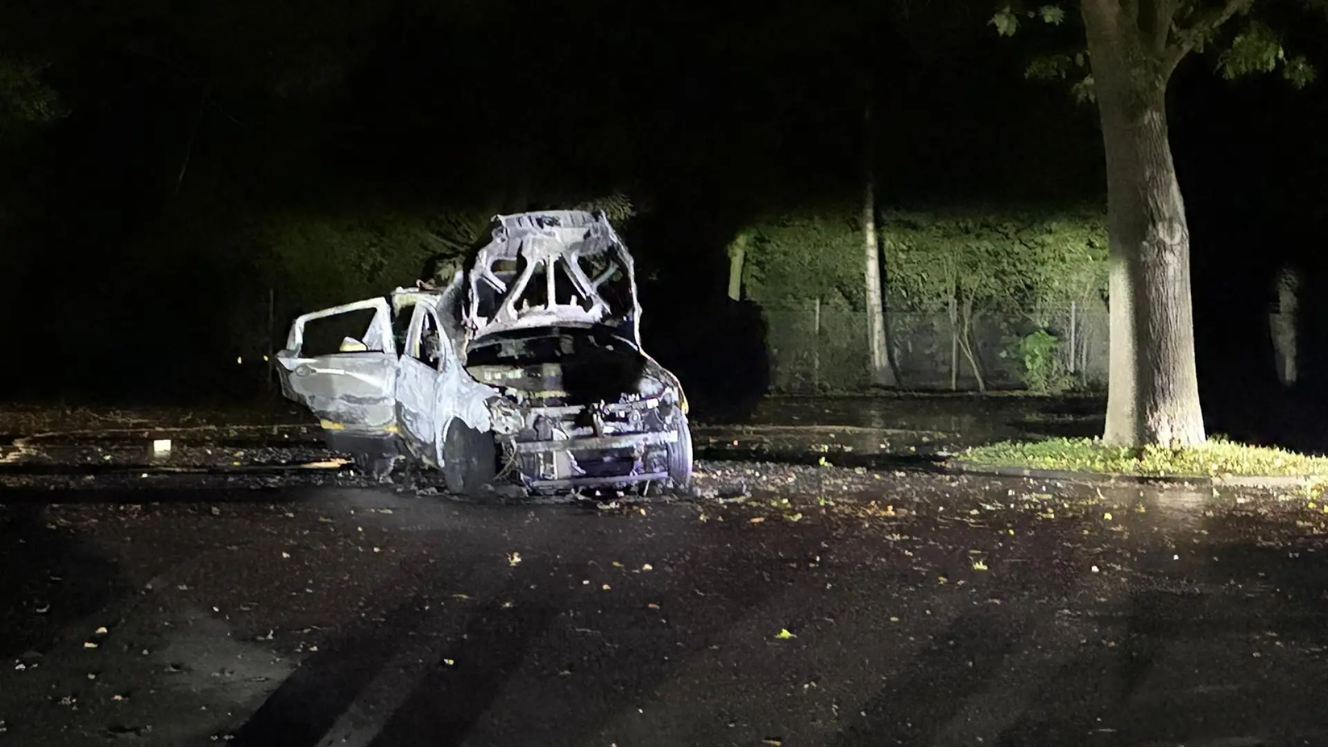01.09.2026, Nordrhein-Westfalen, Mönchengladbach: Ein ausgebranntes Auto steht vor einem Zaun. Ein Mann soll in Mönchengladbach seine Schwägerin getötet und seine Ehefrau lebensgefährlich verletzt haben. Er wurde kurz nach dem tödlichen Streit am Montag (31.08.2026) neben dem noch brennenden Auto von der Polizei entdeckt und festgenommen. Foto: Tim Lehmann/dpa +++ dpa-Bildfunk +++