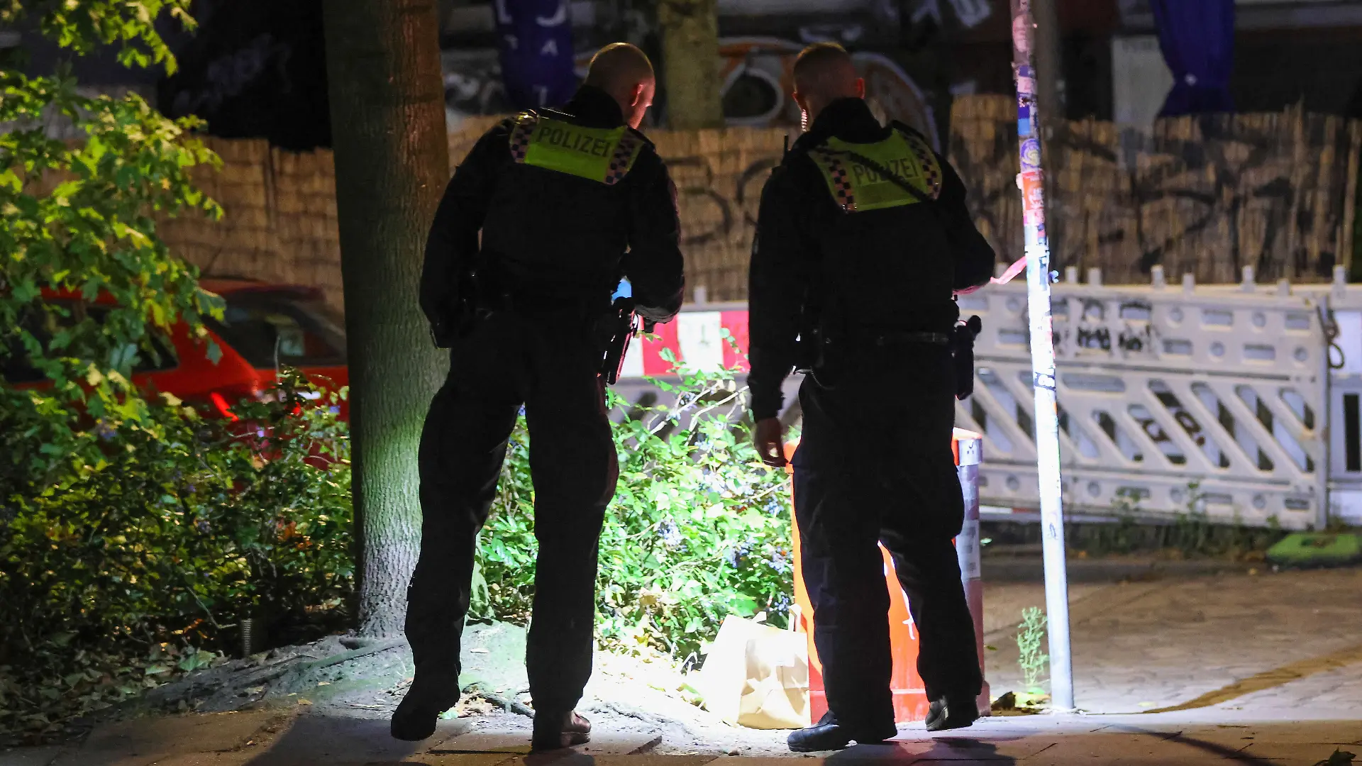 Polizisten suchen in der Nähe des Tatorts und in den umliegenden Straßen mit Taschenlampen nach Spuren.