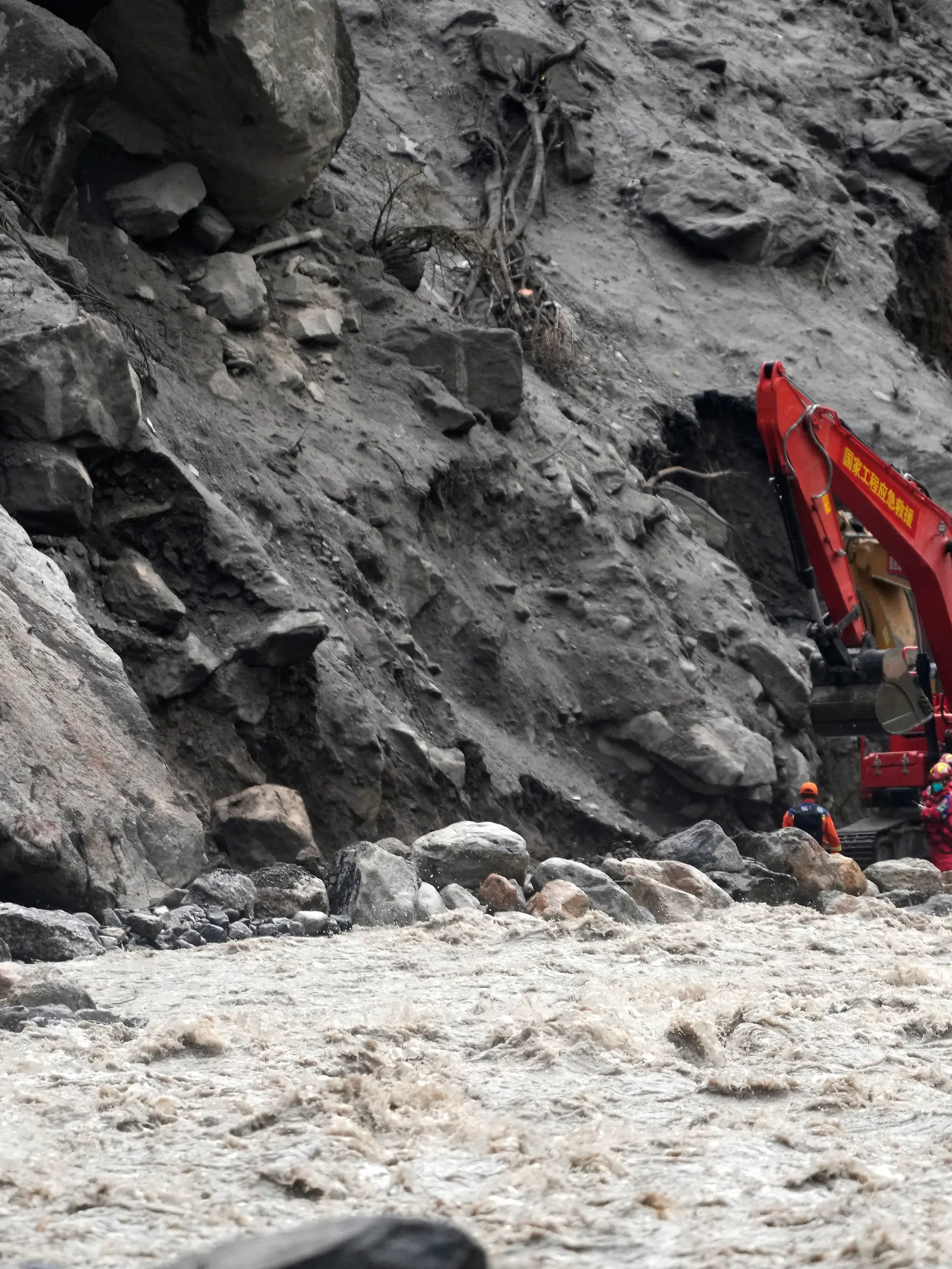 Chinese rescue personnel carrying supplies and equipment enter the core disaster area through a newly opened land route as excavators work at the destroyed Gyirong Port in Gyirong County, in China's western Tibet Autonomous Region, on September 2, 2026. (Photo by CNS / AFP) / China OUT